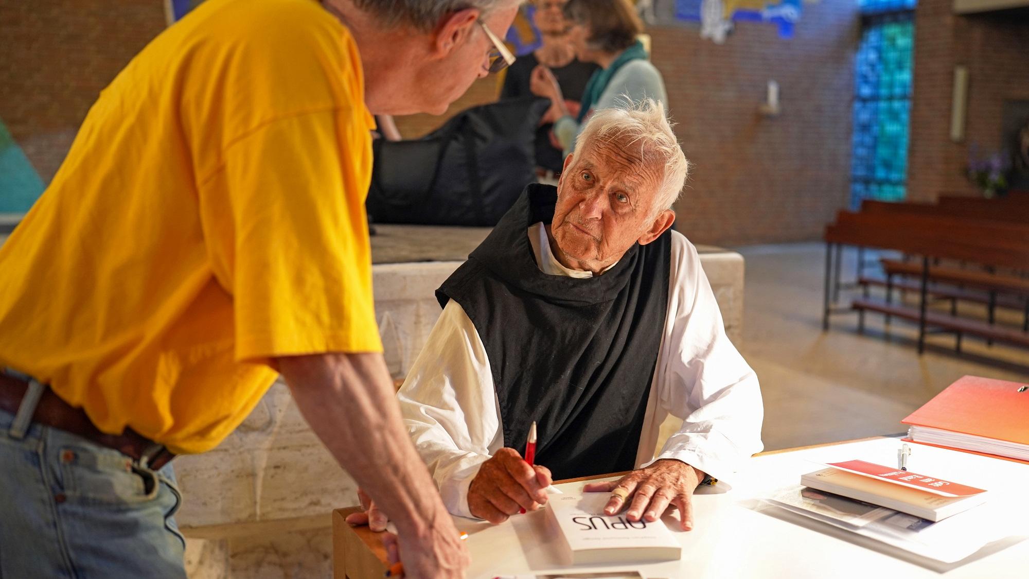 Pater Stephan signiert sein neuestes Buch mit dem Titel „Opus“.