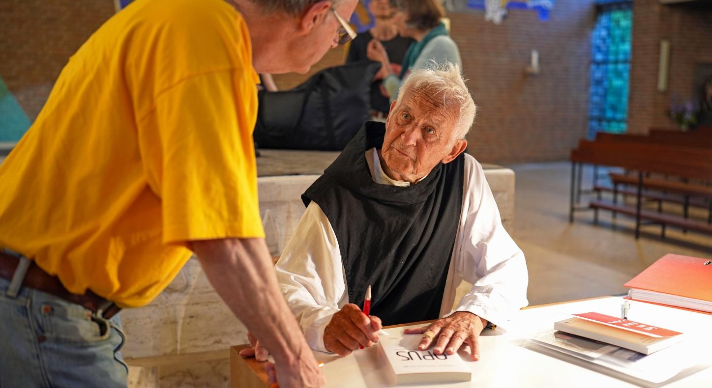 Pater Stephan signiert sein neuestes Buch mit dem Titel „Opus“.