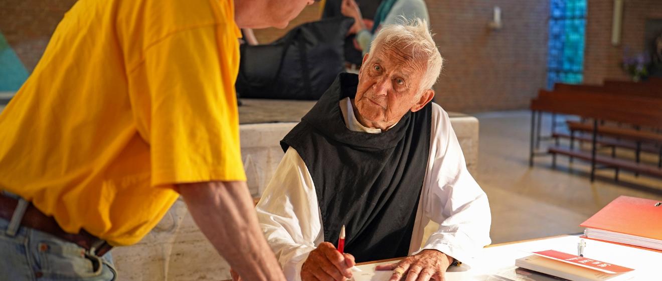 Pater Stephan signiert sein neuestes Buch mit dem Titel „Opus“.