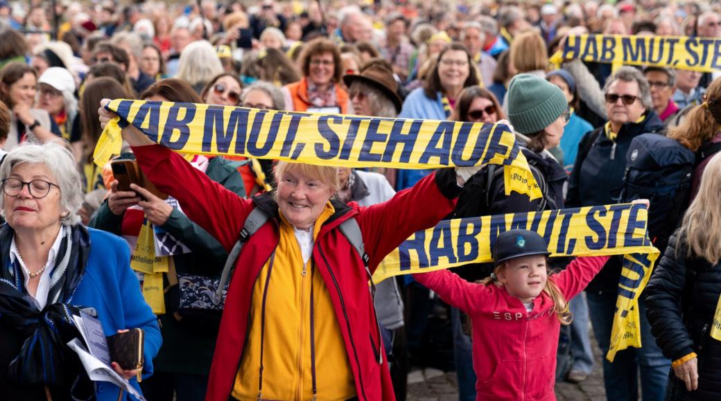 Teilnehmer halten Katholikentags-Schals hoch beim Abschlussgottesdienst am 17. Mai in Würzburg.