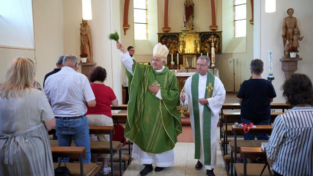 Weihbischof em. Gebert im Innenraum der Pfarrkirche; er segnet sie mit einem Palmzweig