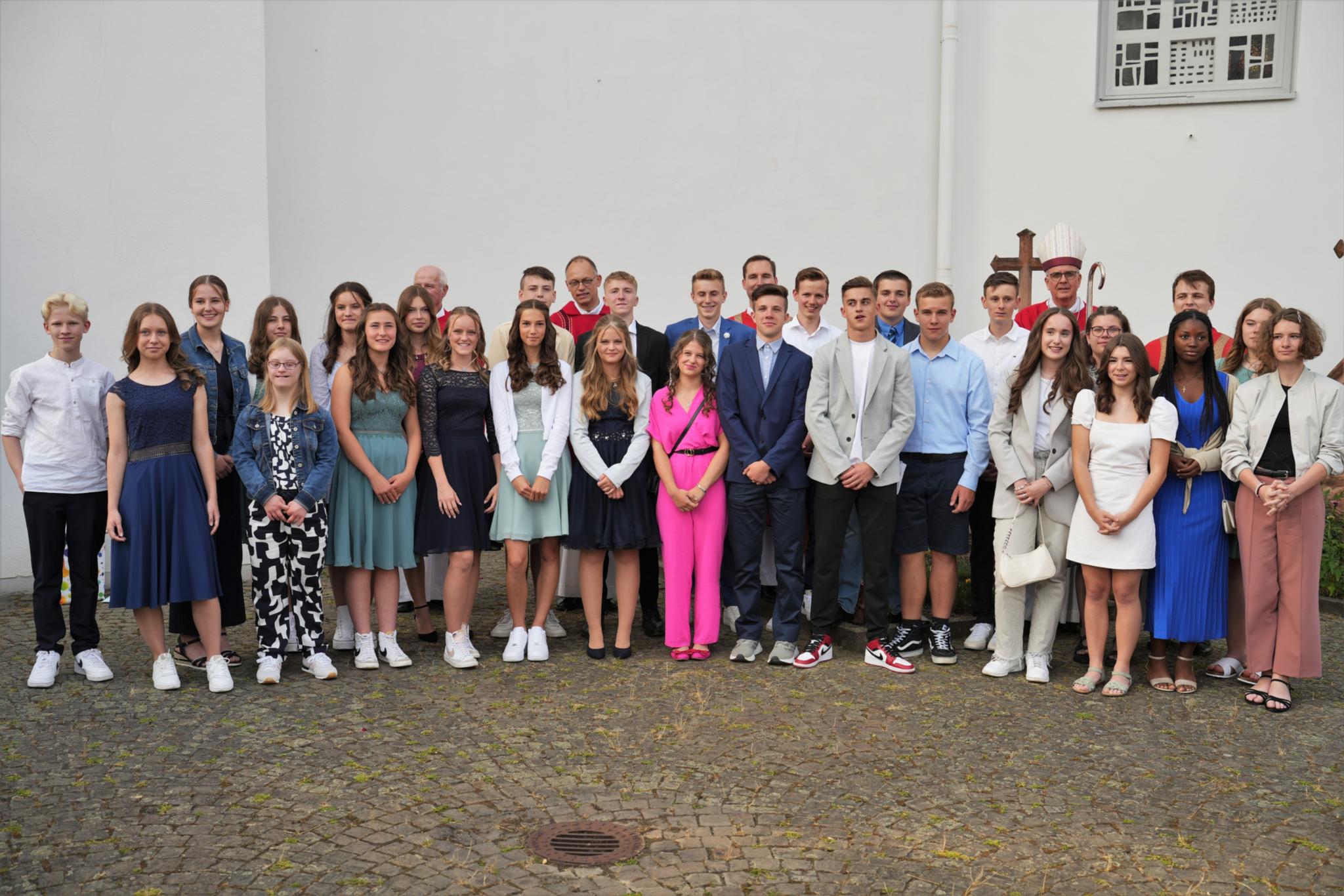 Die Firmlinge nach dem Gottesdienst vor der Lebensbaumkirche, gemeinsam mit dem Weihbischof (mit Mitra) und den Priestern, die sie als Katecheten begleiteten.