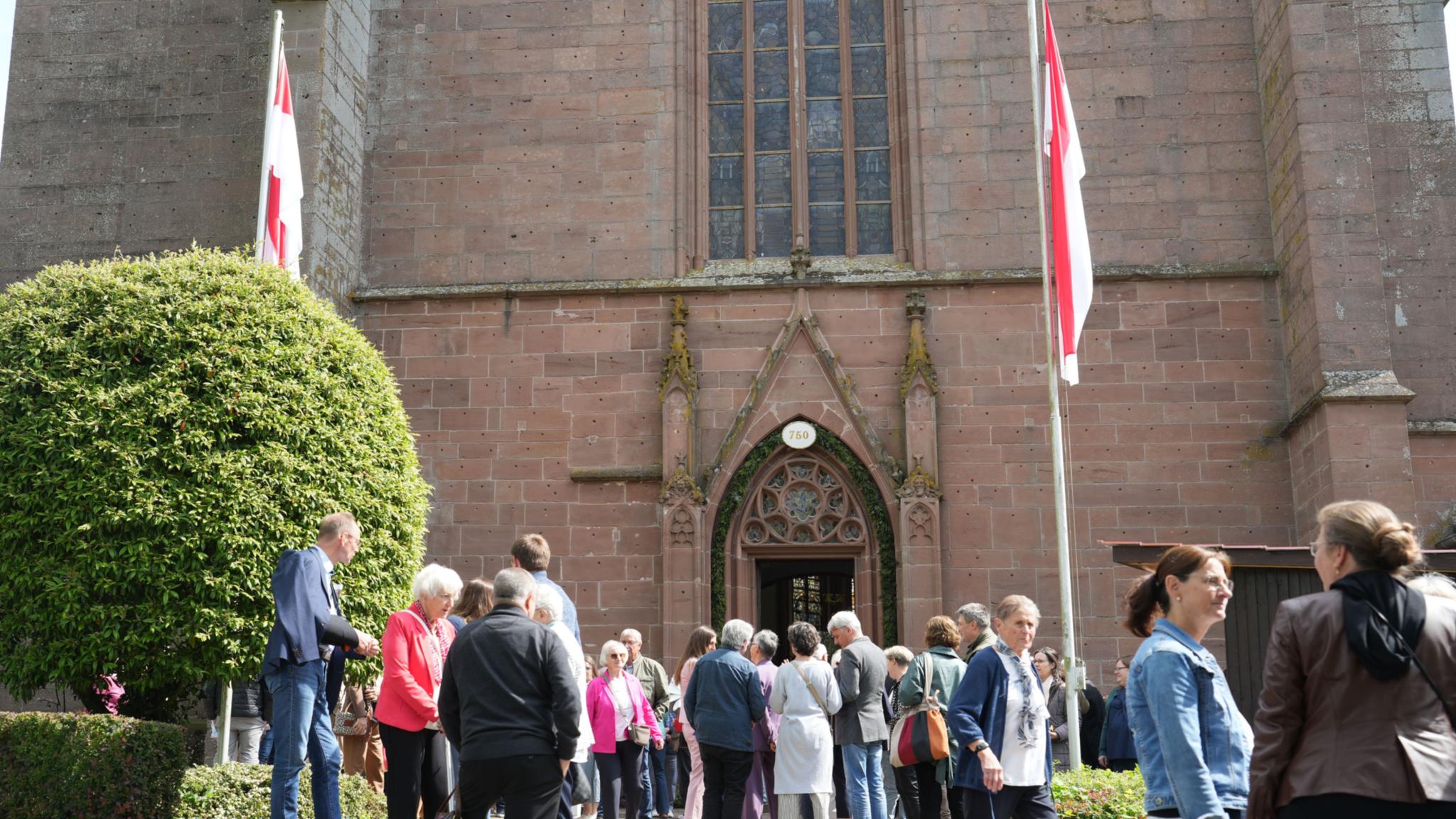 Eine Gruppe von Menschen steht vor dem Eingang der Kirche in Kyllburg