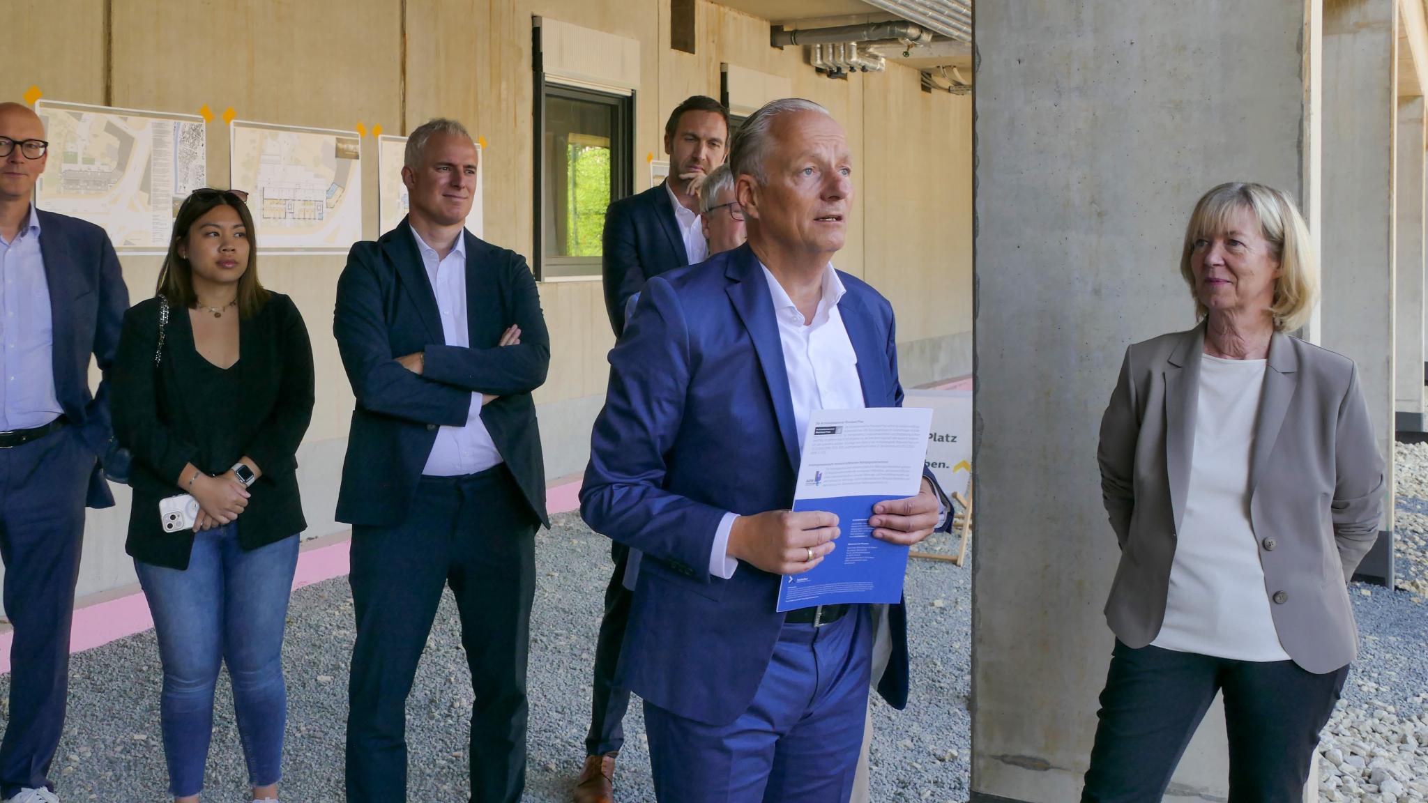 Ein Mann hält eine Rede, mehrere Personen stehen drumherum