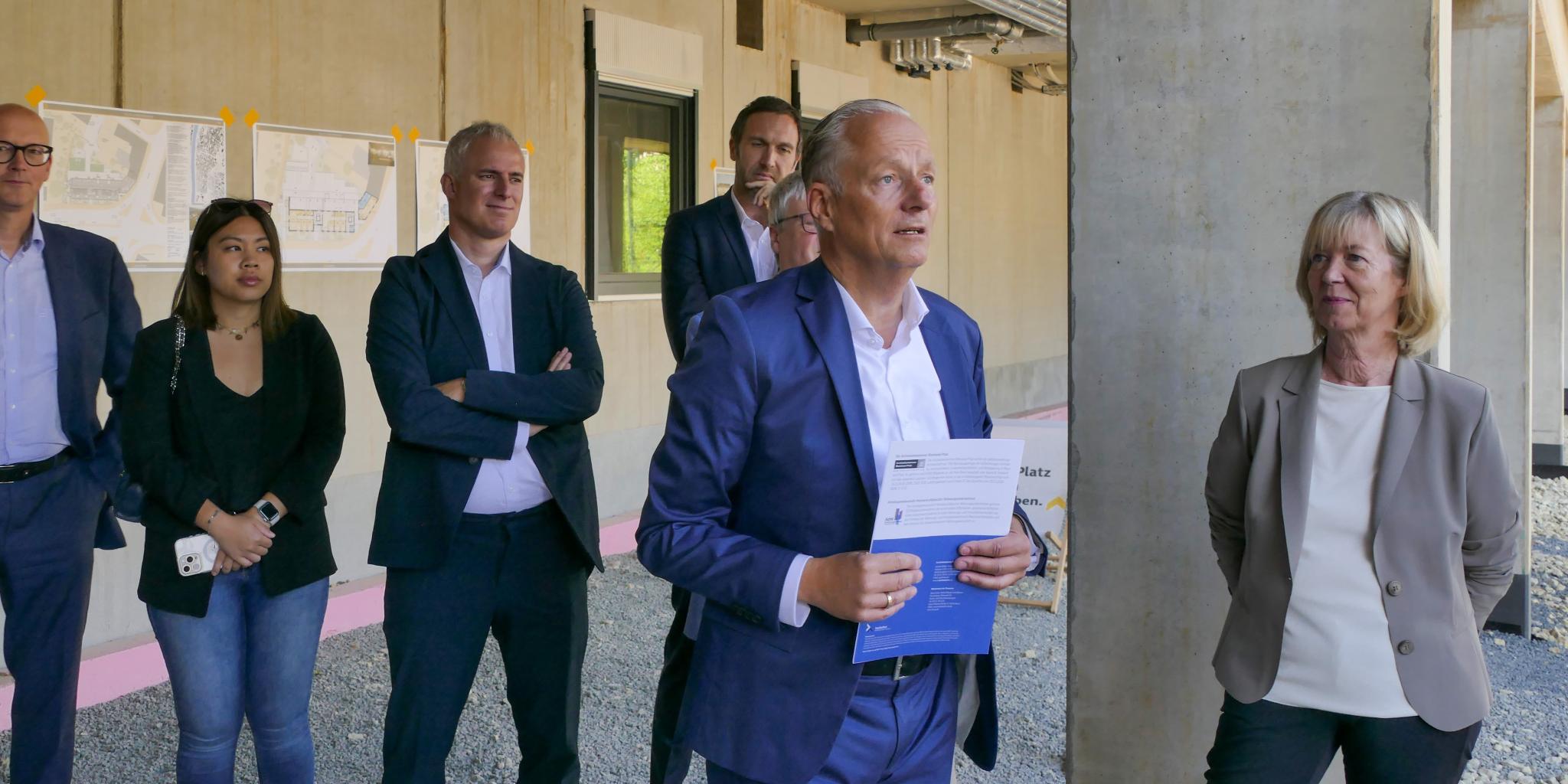 Ein Mann hält eine Rede, mehrere Personen stehen drumherum