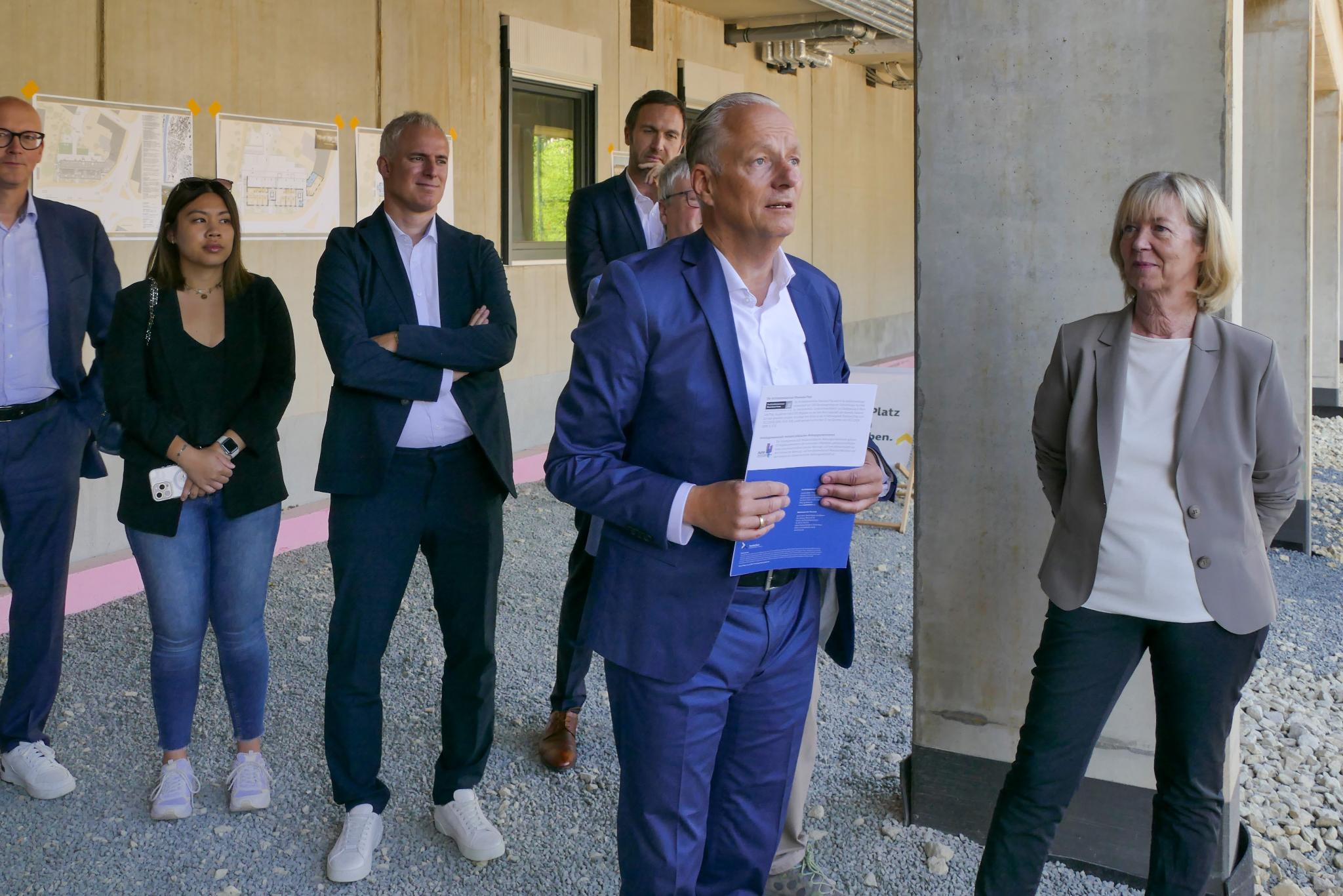 Ein Mann hält eine Rede, mehrere Personen stehen drumherum
