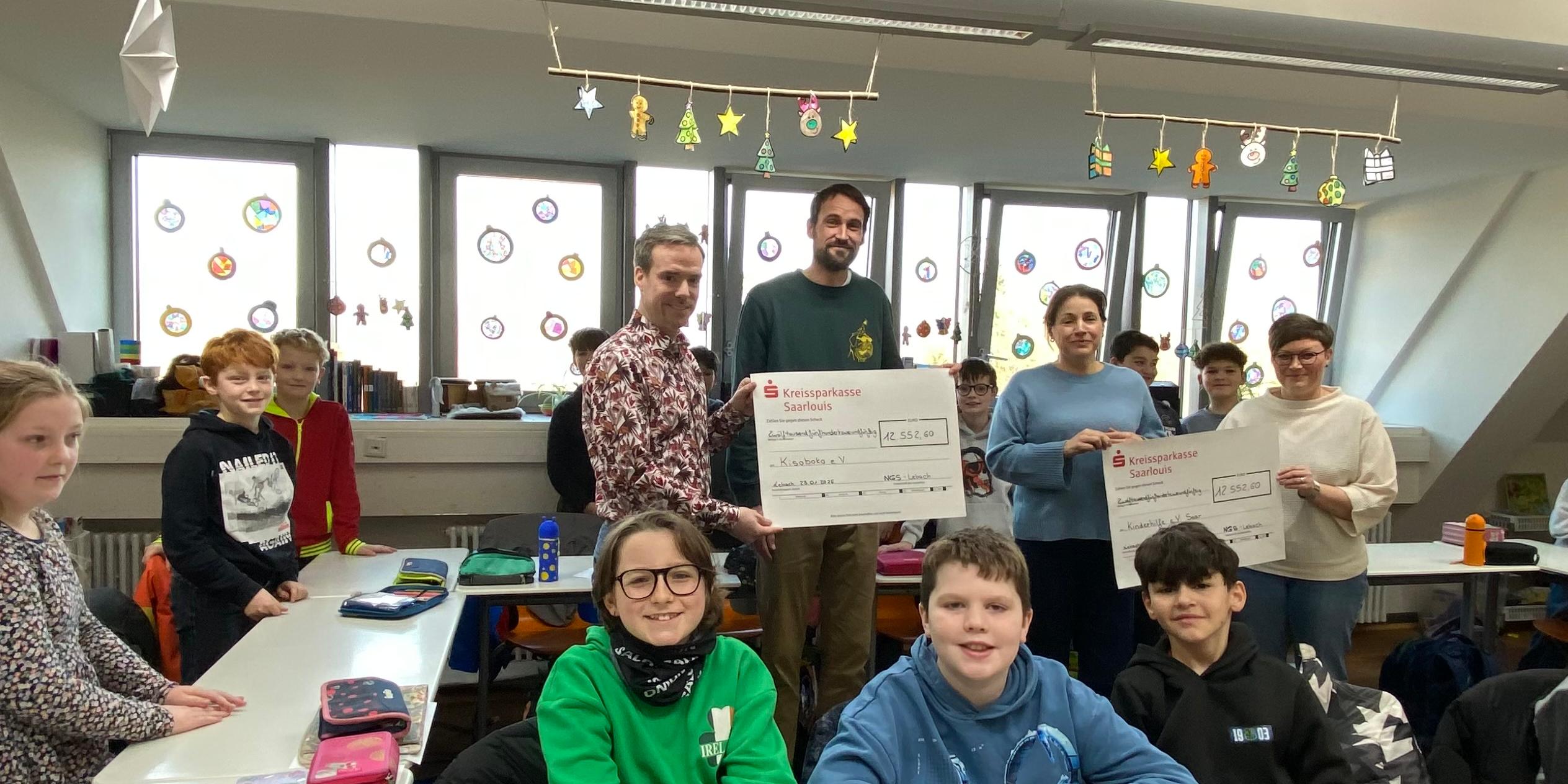 Schülerinnen und Schüler sowie Lehrkräfte der Nikolaus Groß-Schulen in Lebach überreichen Antonia Nutting von Boch (Kinderhilfe Saar) und Lukas Schäfer (Verein Kisoboka, Uganda) symbolisch Schecks mit den Erlösen ihres Spendenlaufs.