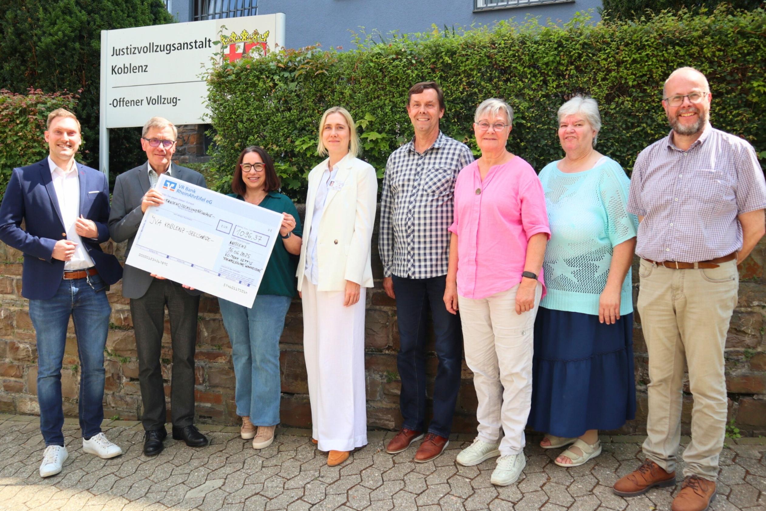 Diakon Frank Lahnstein (Zweiter v. links) freut sich über die Spende des Kirchort-Teams St. Bartholomäus Kettig und der Theatergruppe 'WandelBar' aus Kettig an die katholische Gefängnisseelsorge in der JVA Koblenz. Bei der Scheckübergabe berichten Anstaltsleiter Jörn Omland (links) und die stellvertretende Anstaltsleiterin Carolin Bucksteeg (Vierte v. links) von ihrer Arbeit und dem Alltag in der JVA.