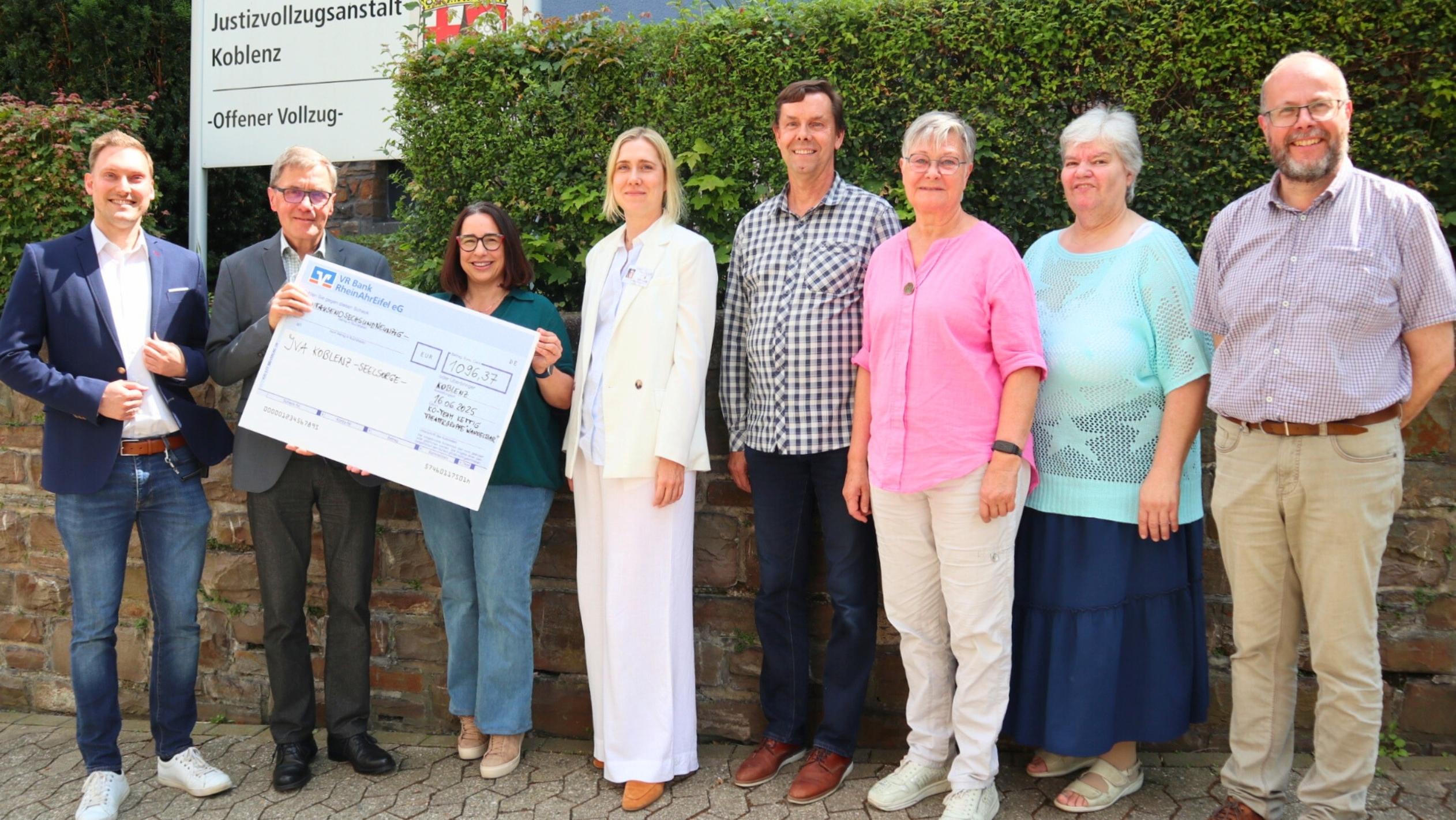 Diakon Frank Lahnstein (Zweiter v. links) freut sich über die Spende des Kirchort-Teams St. Bartholomäus Kettig und der Theatergruppe 'WandelBar' aus Kettig an die katholische Gefängnisseelsorge in der JVA Koblenz. Bei der Scheckübergabe berichten Anstaltsleiter Jörn Omland (links) und die stellvertretende Anstaltsleiterin Carolin Bucksteeg (Vierte v. links) von ihrer Arbeit und dem Alltag in der JVA.