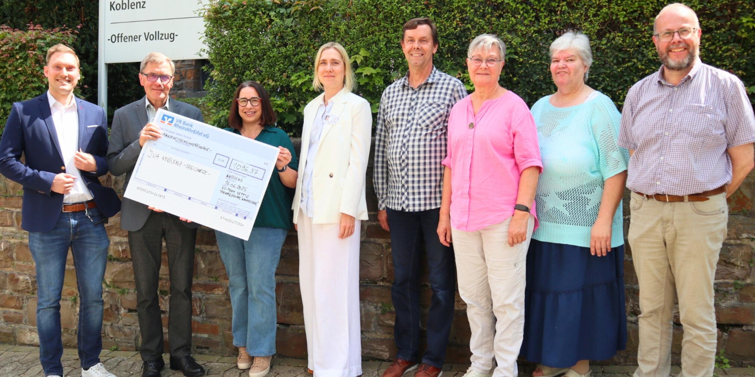 Diakon Frank Lahnstein (Zweiter v. links) freut sich über die Spende des Kirchort-Teams St. Bartholomäus Kettig und der Theatergruppe 'WandelBar' aus Kettig an die katholische Gefängnisseelsorge in der JVA Koblenz. Bei der Scheckübergabe berichten Anstaltsleiter Jörn Omland (links) und die stellvertretende Anstaltsleiterin Carolin Bucksteeg (Vierte v. links) von ihrer Arbeit und dem Alltag in der JVA.