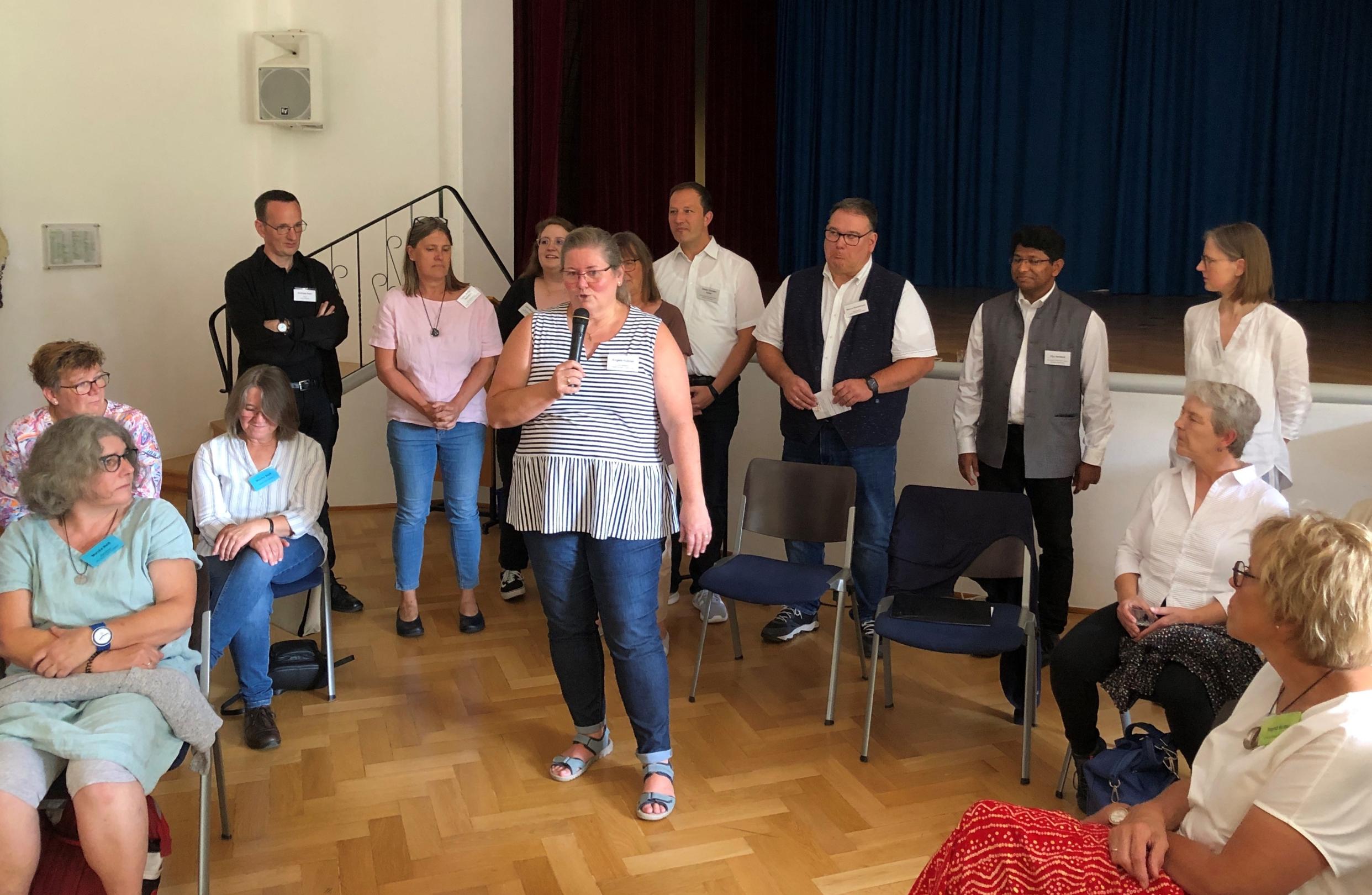 Angela Hübner vom Leitungsteam bei der Begrüßung, im Hintergrund Mitglieder des Leitungs- und des Seelsorge-Teams