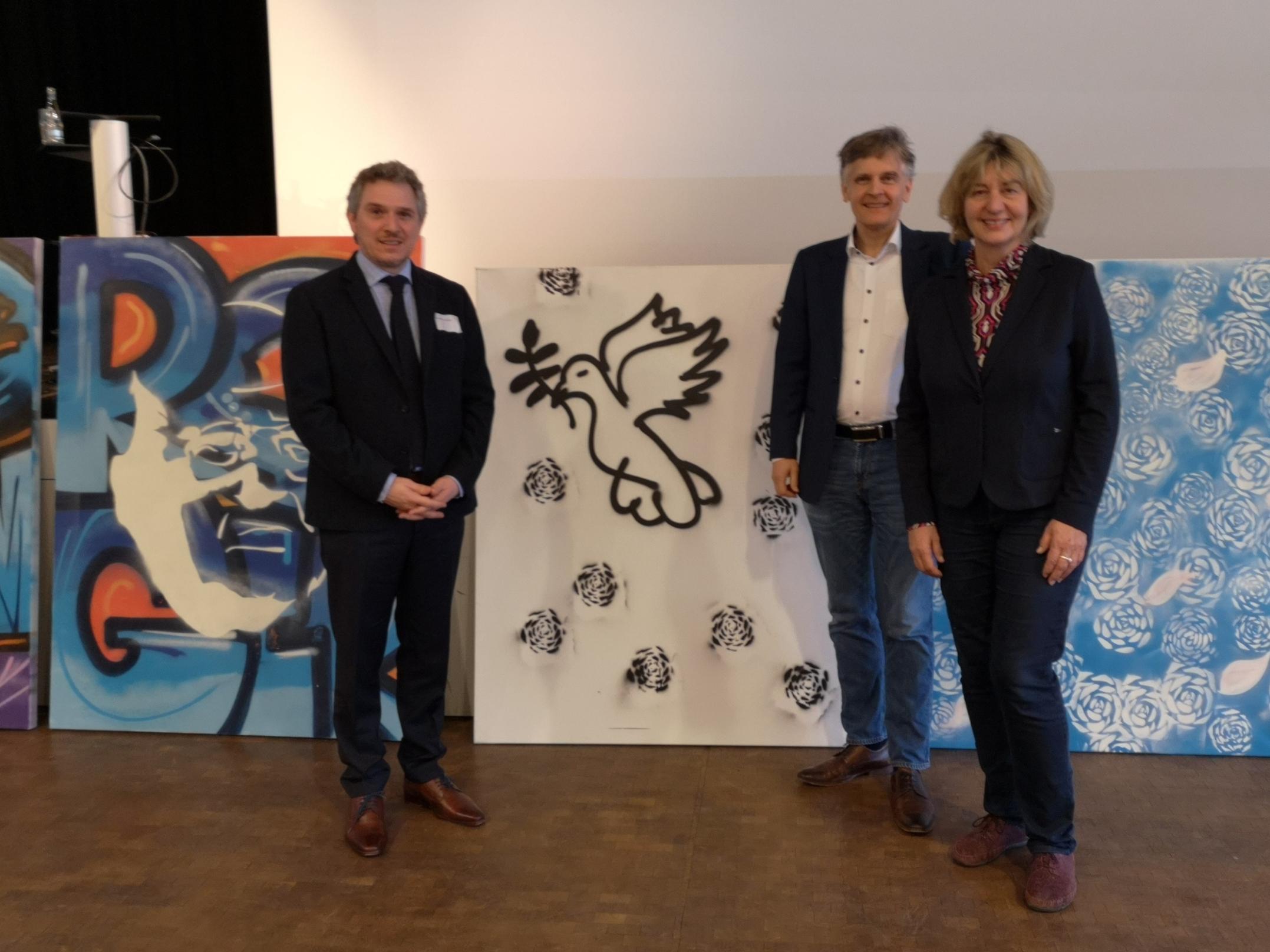 Mit-)Ausrichter PD Dr. Alexander Maier (Fachrichtung Kath. Theologie) und Prof. Dr. Karlo Meyer (Fachrichtung Ev. Theologie) mit Referentin Prof. Dr. Elisabeth Naurath (Universität Augsburg), im Hintergrund einige Streetart-Kunstwerke, die in der Kirche der Jugend eli.ja entstanden.