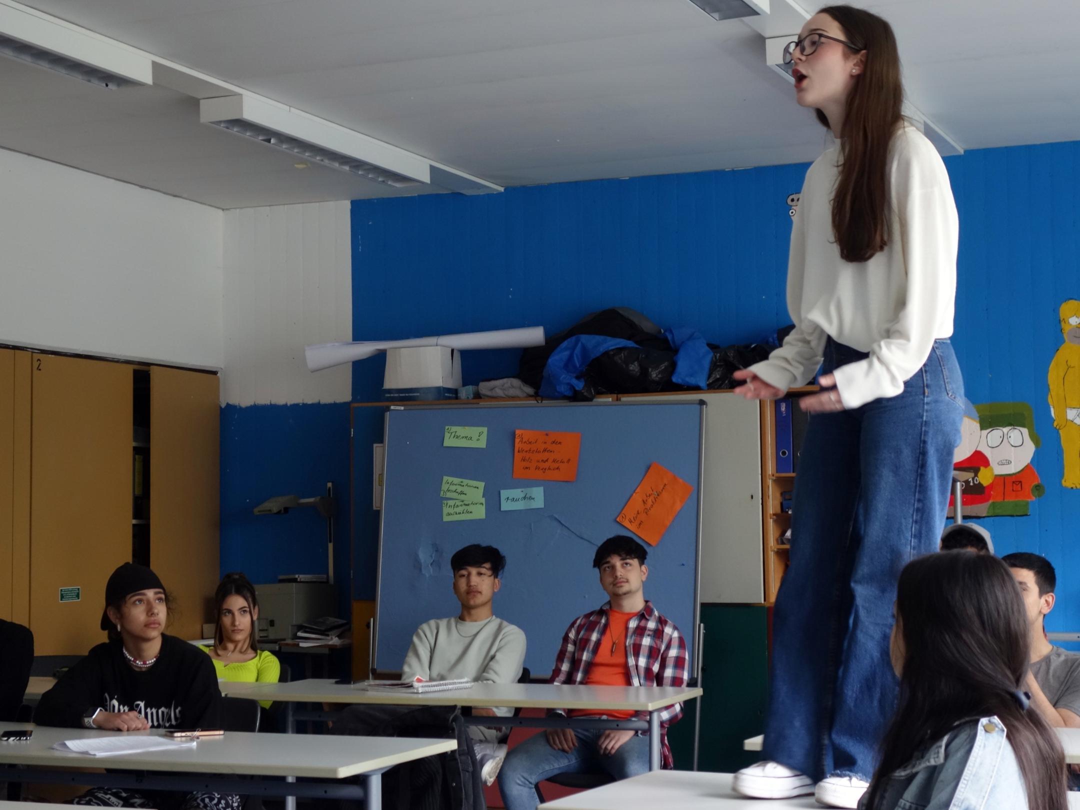 Ein Mädchen steht in einem Klassenraum auf dem Tisch.