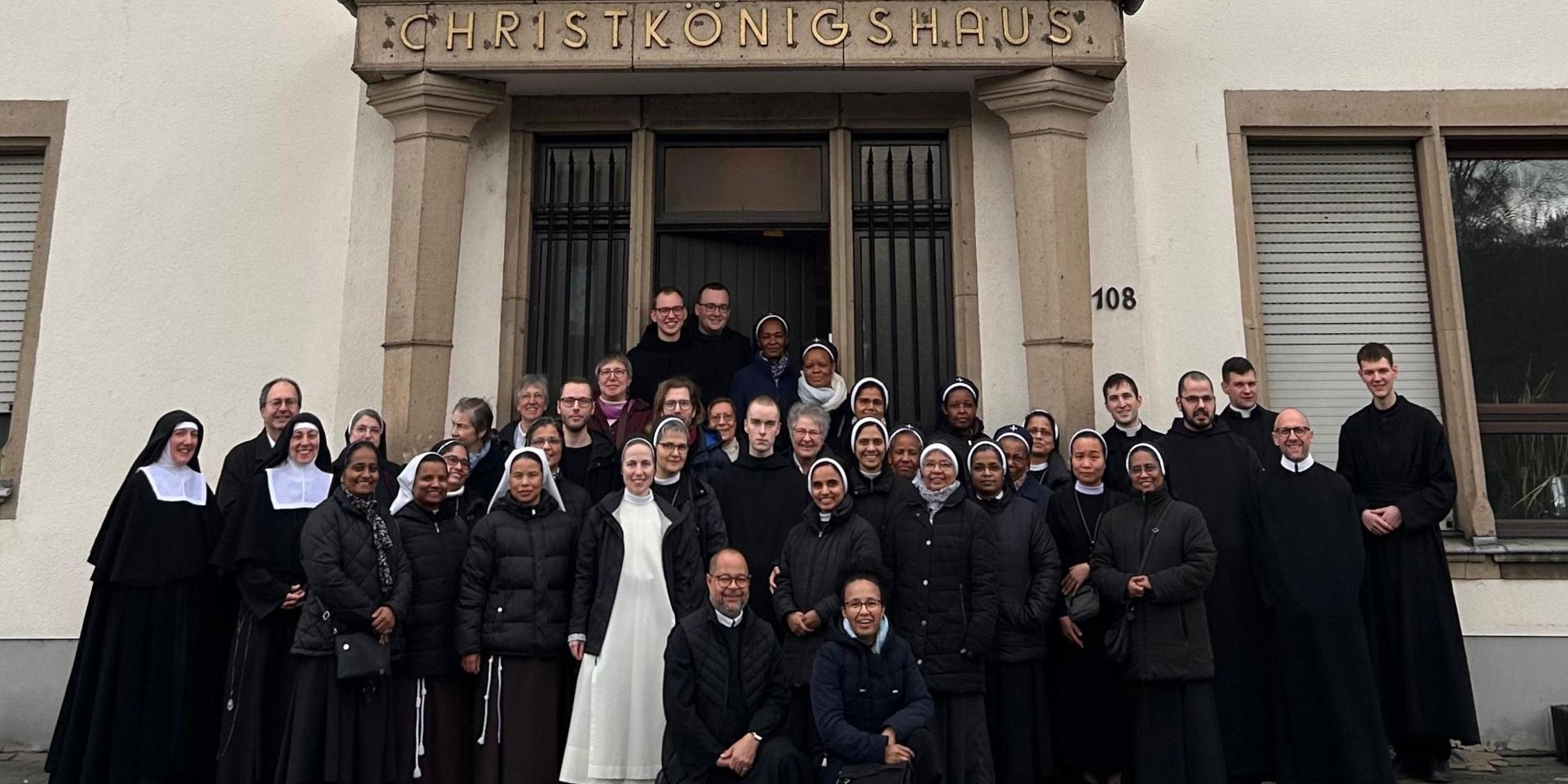 Frauen und Männer mit überwiegend schwarzen Roben stehen vor einer Tür.