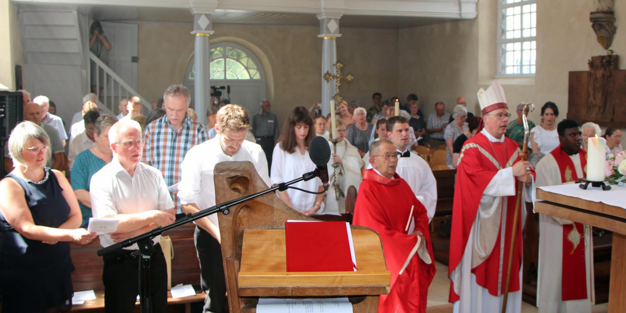 Blick vom Altarraum in eine Kirche, in der Menschen stehen.