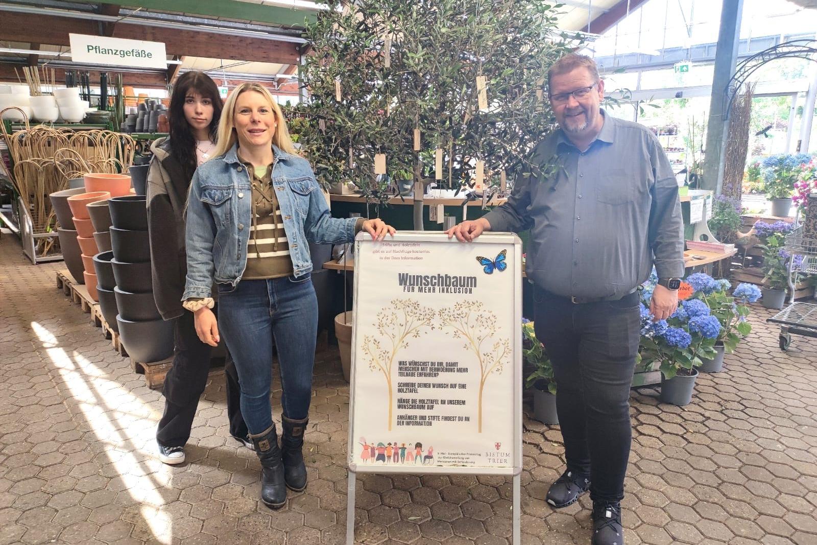 Die Tonpost im Gartenzentrum:  Emily Reimann, FSJlerin in der Tonpost, Kathrin Schmitt, Leiterin der Tonpost und Martin Oed, Geschäftsführer Lambert, haben mit dem Wunschbaum ein Zeichen für mehr Inklusion gesetzt.