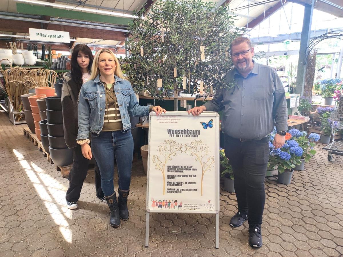 Die Tonpost im Gartenzentrum:  Emily Reimann, FSJlerin in der Tonpost, Kathrin Schmitt, Leiterin der Tonpost und Martin Oed, Geschäftsführer Lambert, haben mit dem Wunschbaum ein Zeichen für mehr Inklusion gesetzt.