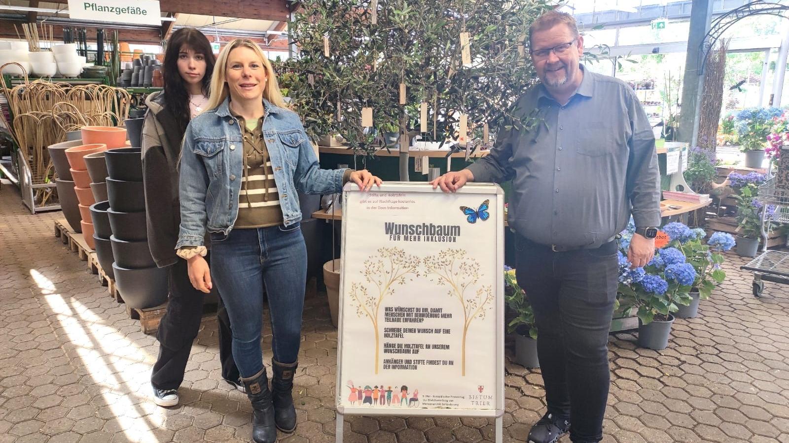 Die Tonpost im Gartenzentrum:  Emily Reimann, FSJlerin in der Tonpost, Kathrin Schmitt, Leiterin der Tonpost und Martin Oed, Geschäftsführer Lambert, haben mit dem Wunschbaum ein Zeichen für mehr Inklusion gesetzt.