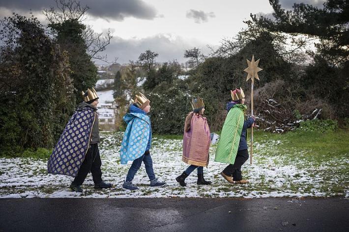 Vier verkleidete Sternsinger, die durch die Straßen ziehen