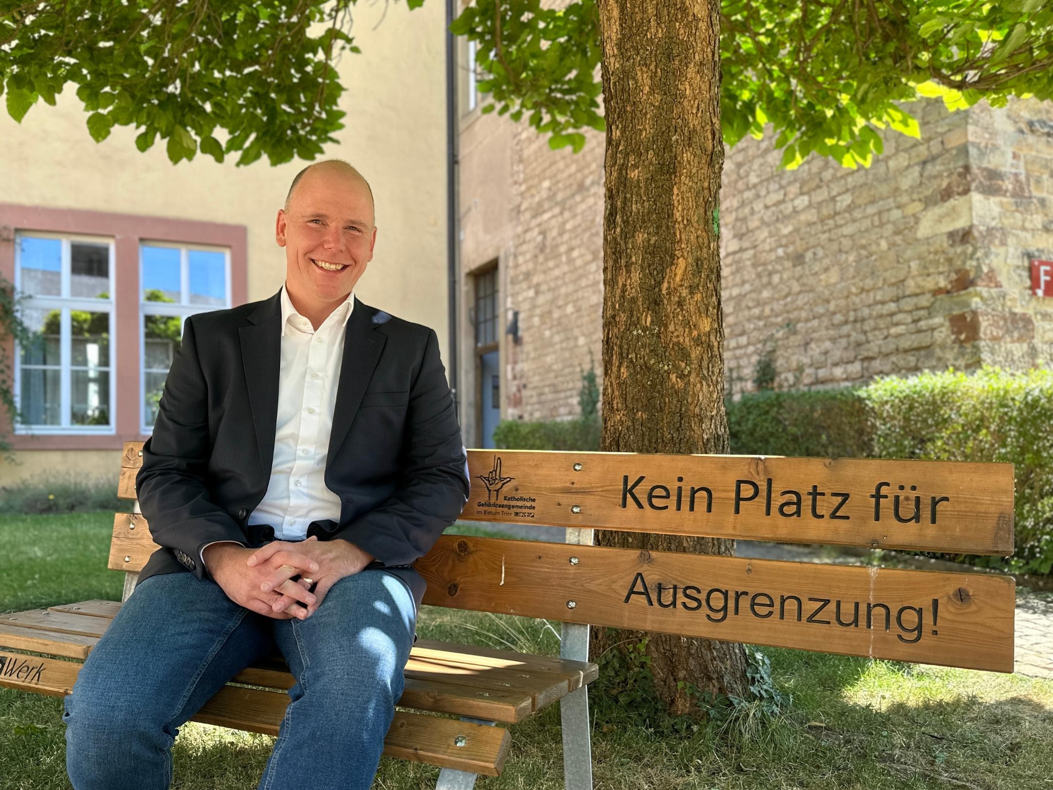 Torsten Wahl auf einer Bank sitzend mit dem Schriftzug 'Kein Platz für Ausgrenzung'