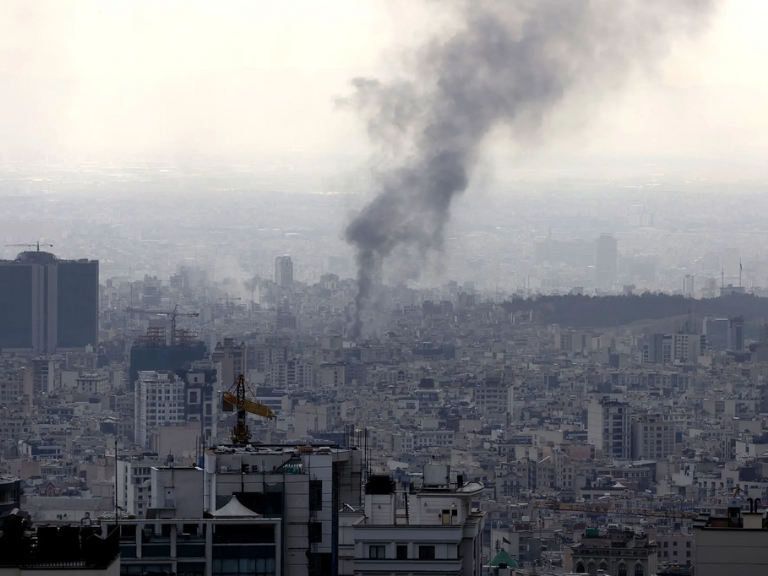 Rauch steigt über dicht bebauter Stadtlandschaft in den Himmel.