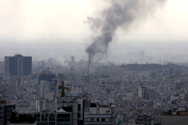 Rauch steigt über dicht bebauter Stadtlandschaft in den Himmel.