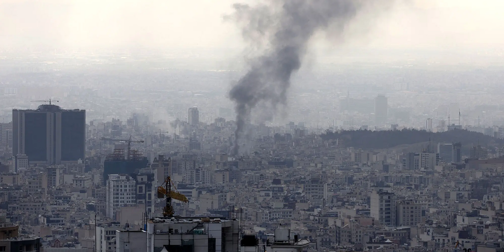 Rauch steigt über dicht bebauter Stadtlandschaft in den Himmel.