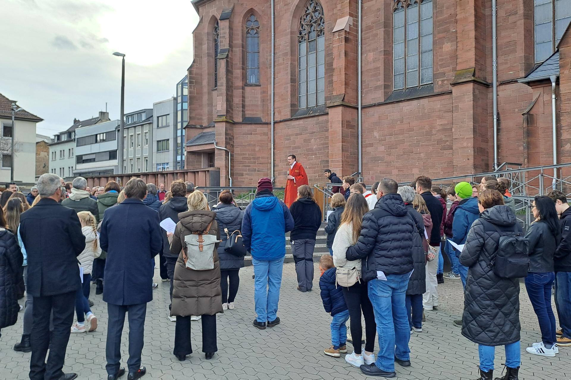 Eine Gruppe von Menschen steht auf dem Platz vor einer Kirche