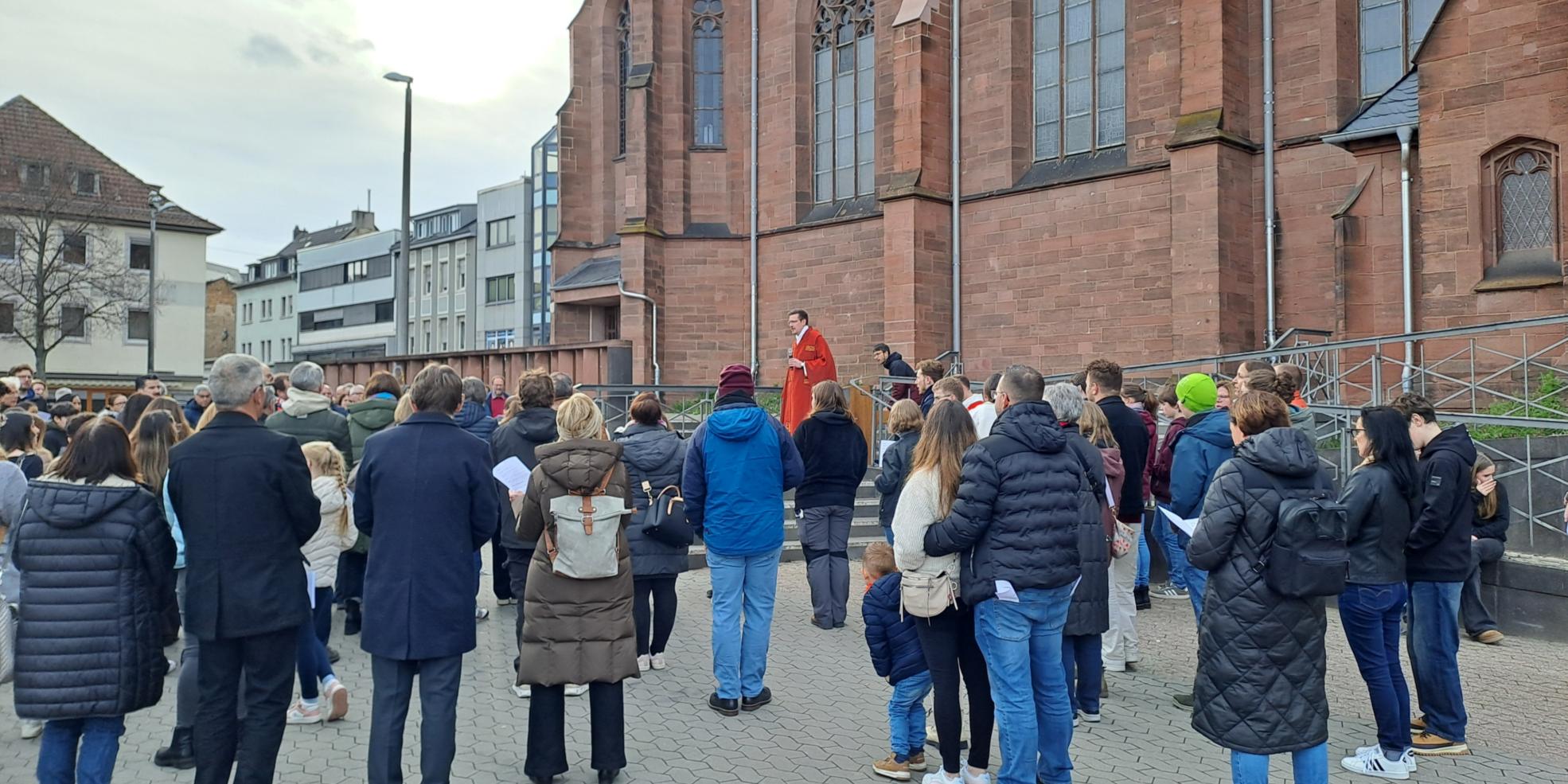 Eine Gruppe von Menschen steht auf dem Platz vor einer Kirche
