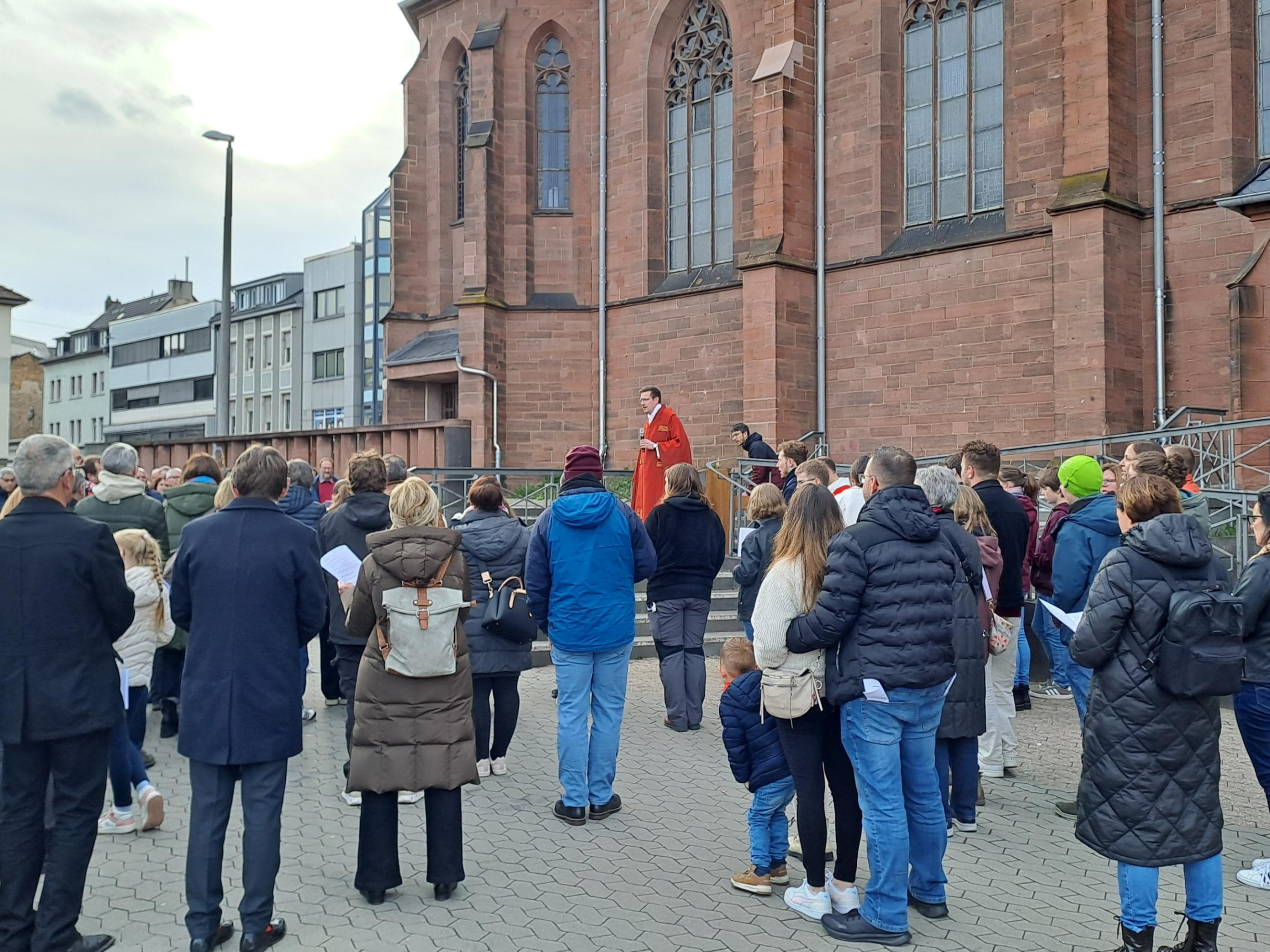 Eine Gruppe von Menschen steht auf dem Platz vor einer Kirche