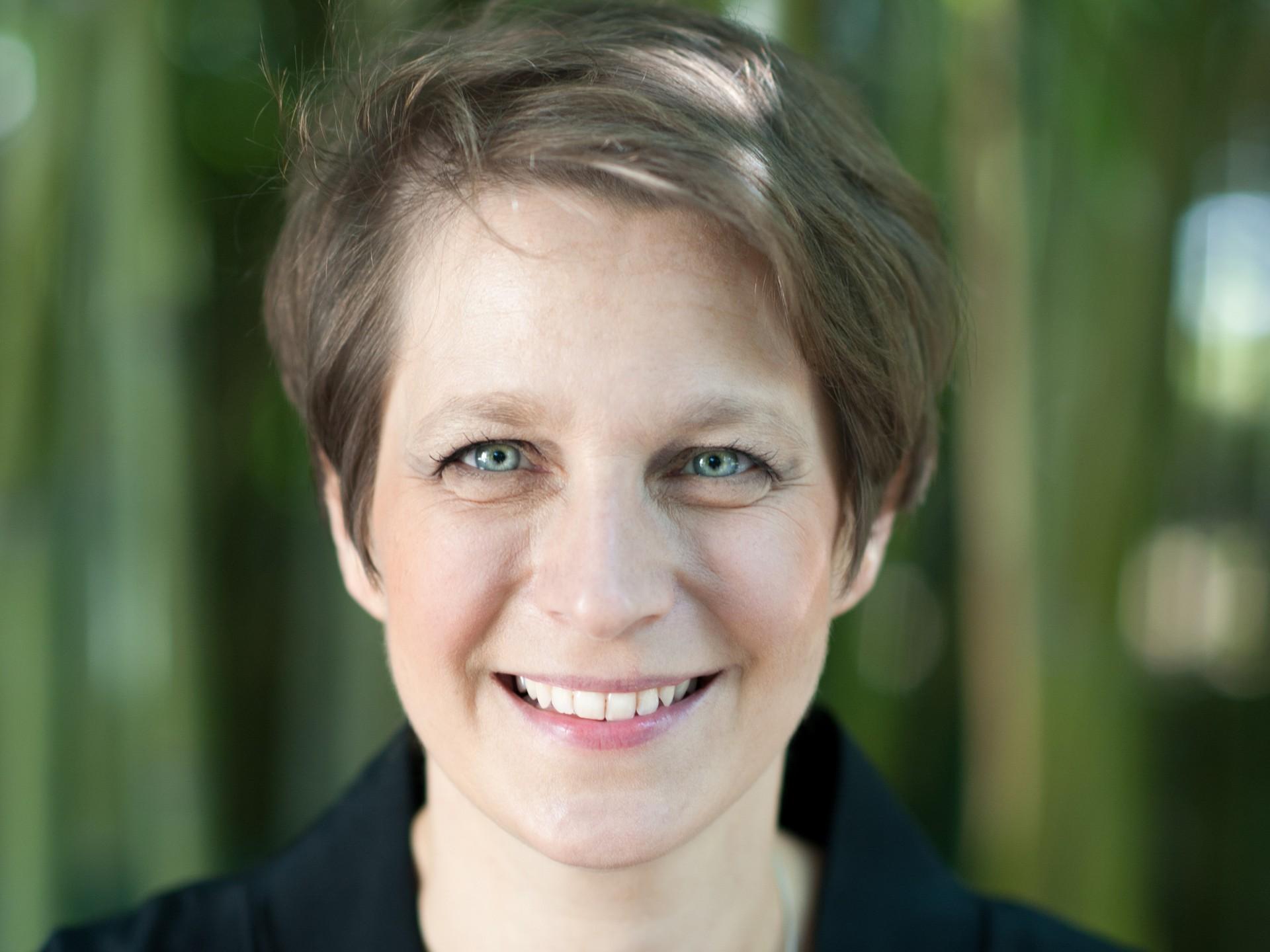 Eine Frau mit kurzen Haaren lächelt in die Kamera