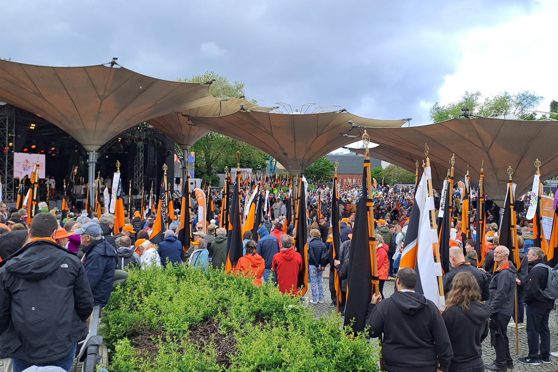 Viele Menschen stehen mit Kolping-Fahnen vor einer Open Air Bühne