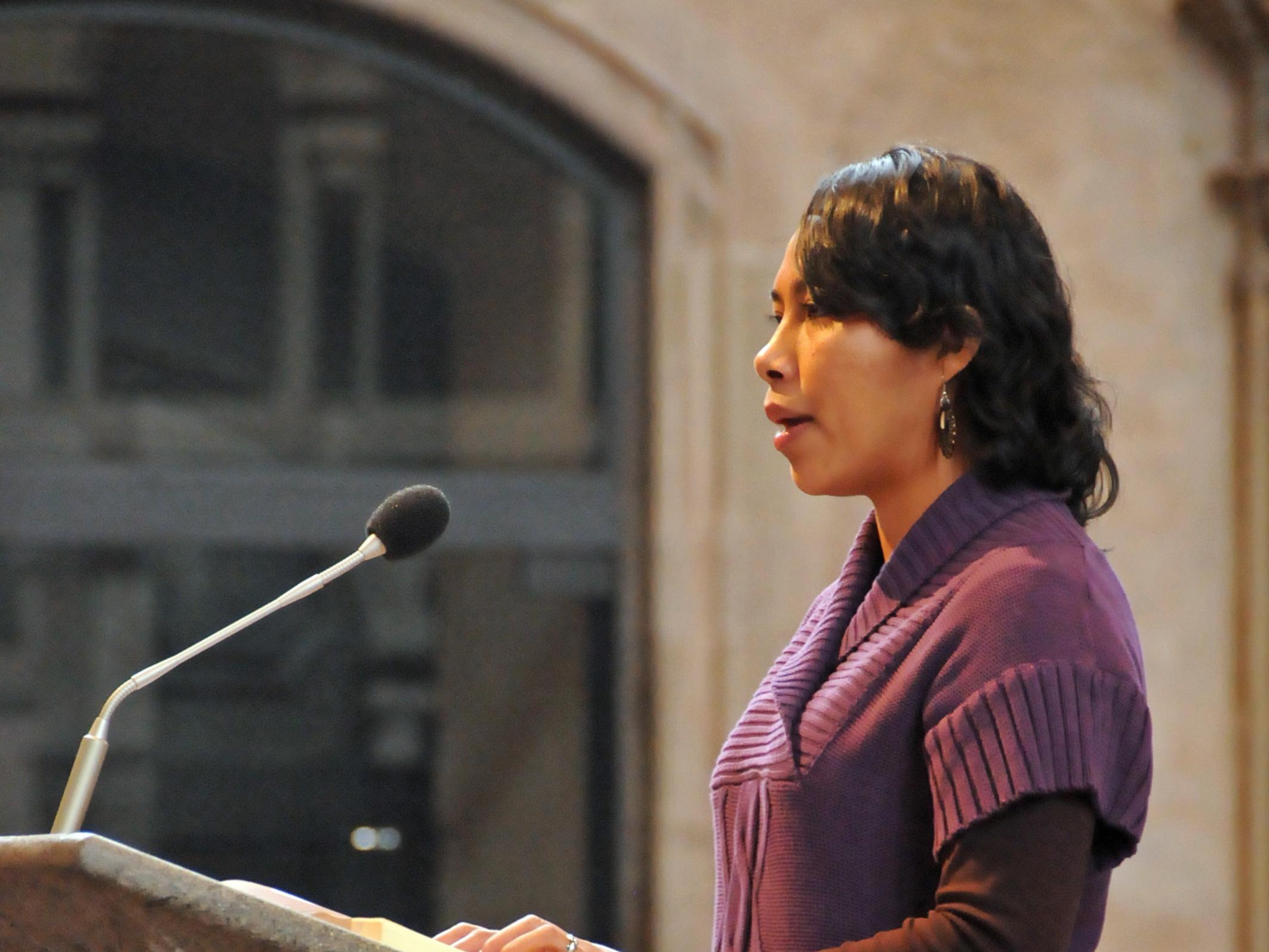 Frau spricht an einem steinernen Ambo in einer Kirche ins Mikrofon.