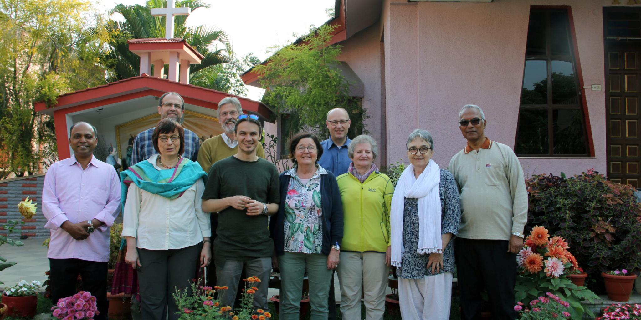 Gruppe Menschen vor pinkem Gebäude mit Blumen