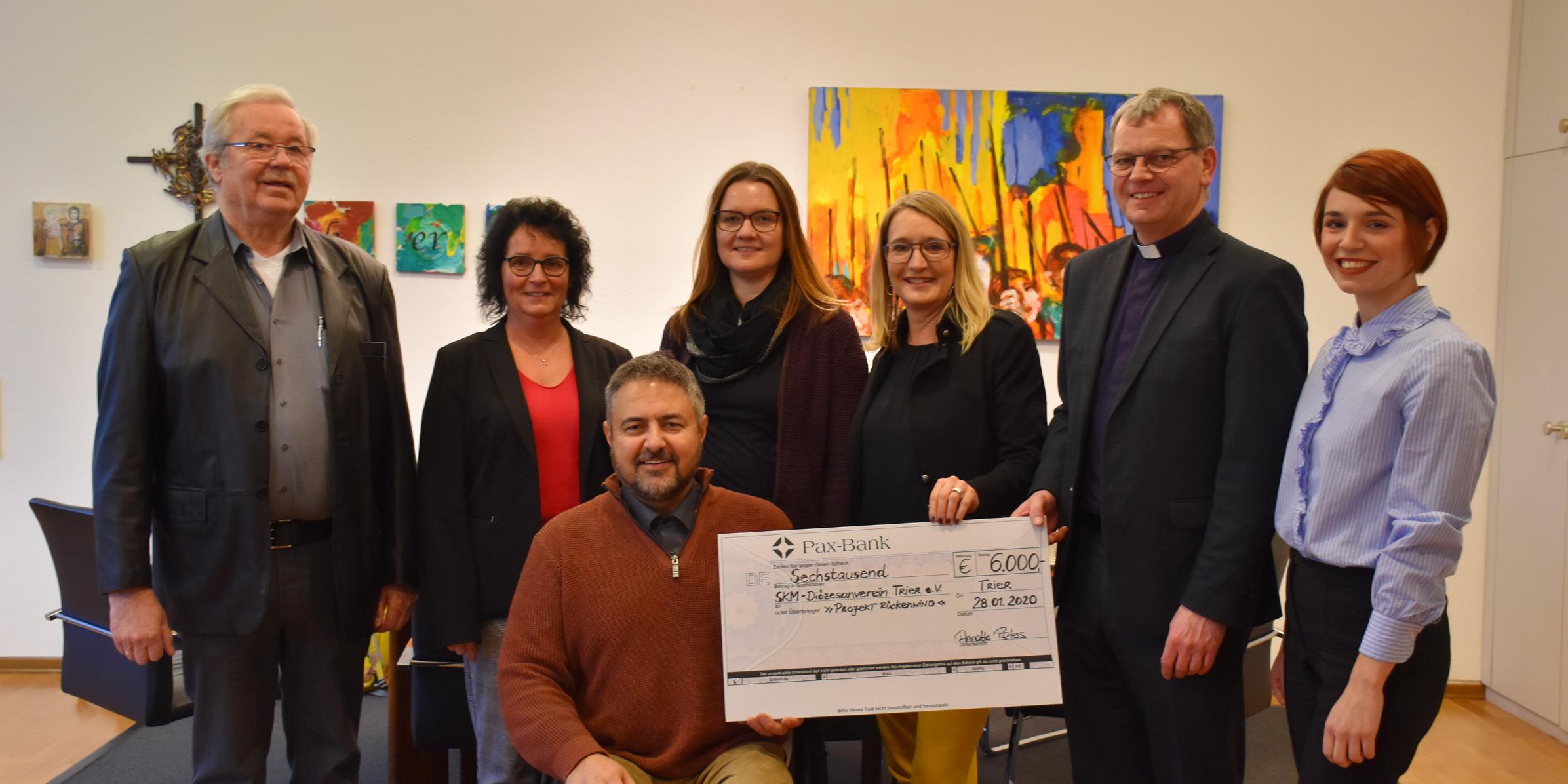 Während der Scheckübergabe - Rolf Richartz von der SKFM Wittlich, die Diözesanreferentin Stephanie Löwen, der Vorsitzende des SKM-Diözesanvereins Helmut Müller, Melanie Begon von „Rückenwind“, die Geschäftsführerin des Paulinus-Verlags Annette Peters, Generalvikar Dr. Ulrich Graf von Plettenberg und Katharina Bauer vom Paulinus-Verlag (vlnr).