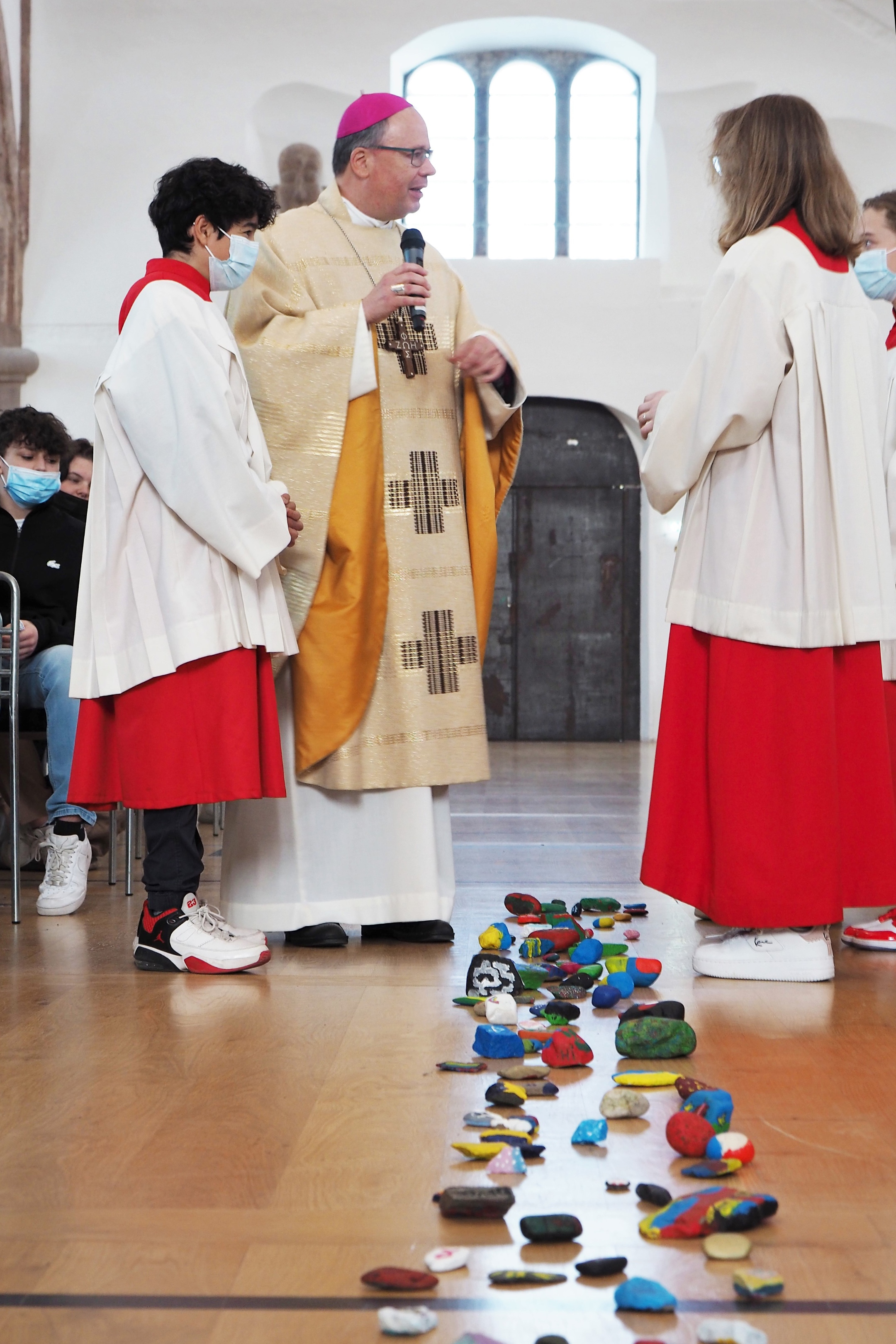 Bischof Ackermann unterhält sich mit einigen Ministranten, die individuell gestaltete Steine für den Gottesdienst ausgelegt haben (Foto: Stefan Endres/Bistum Trier)