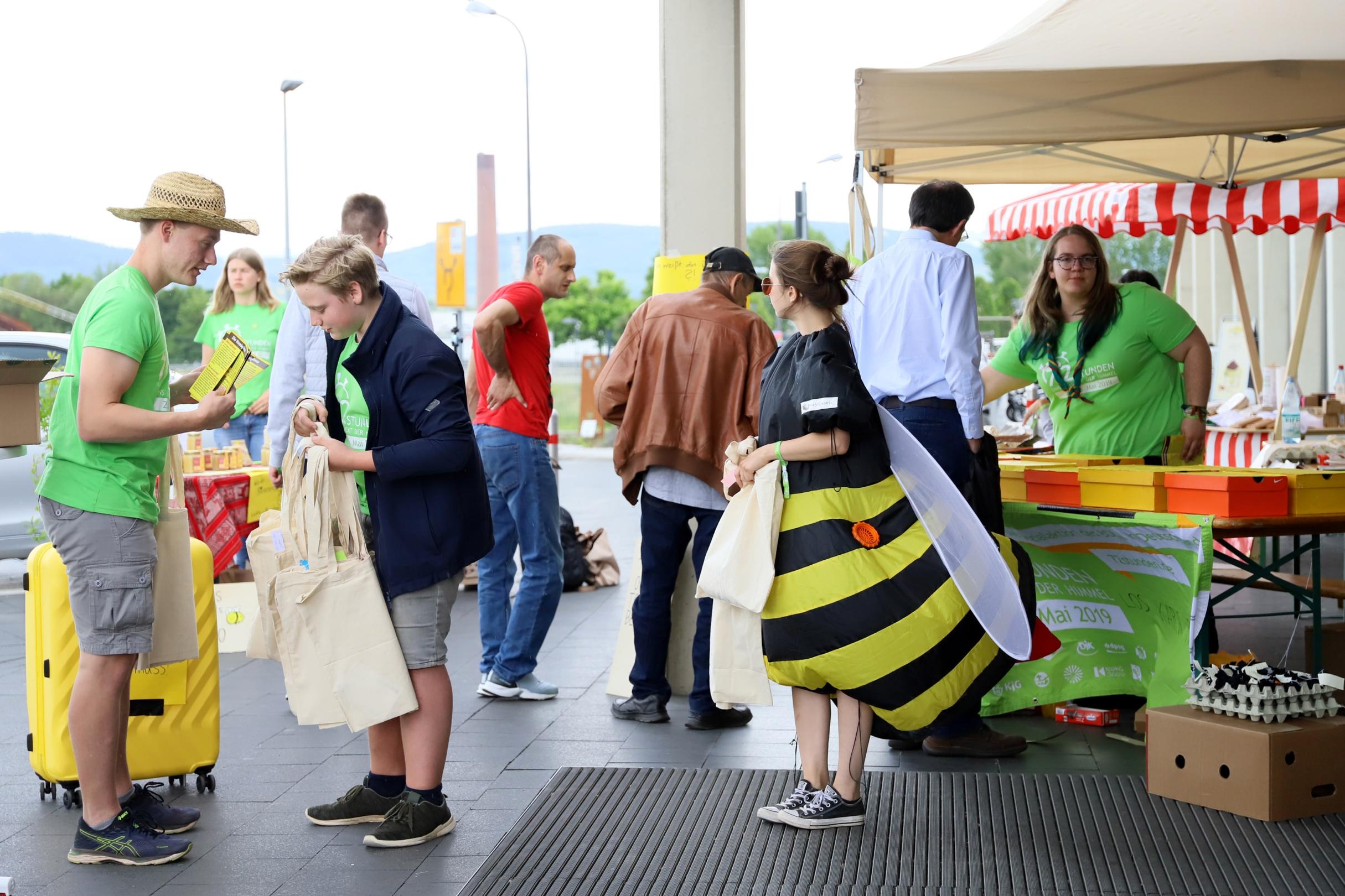 Die jungen Leute mit ihrem Aktionsstand vor dem Bungert. Die Brüder Fabian udn Silas (links) verteilen Flyer, Tamara klärt beim Bienenquezz auf (rechts) und Pauline trägt heute mal Bienenkostüm