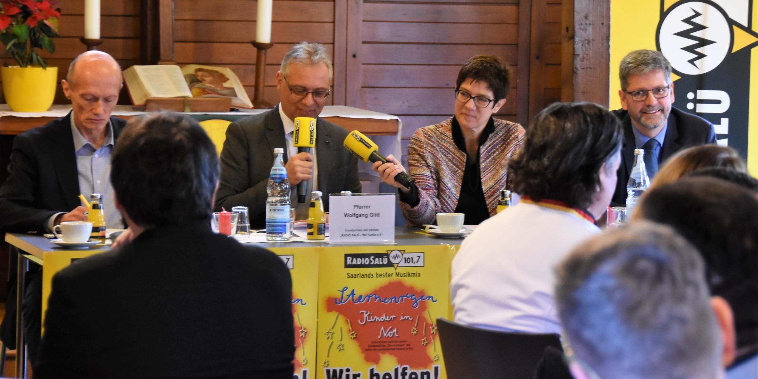 Man hilft sich: Ministerpräsidentin Annegret Kramp-Karrenbauer hält Pfarrer Wolfgang Glitt, dem Vorsitzende des Vereins Radio Salü Wir helfen e.V. das zweite Mikrofon. Daneben Wolfgang Schütz, Direktor des Caritas-Verbands Schaumberg-Blies (l.) und der Geschäftsführer von Radio Salü, Michael Mezödi(r.).