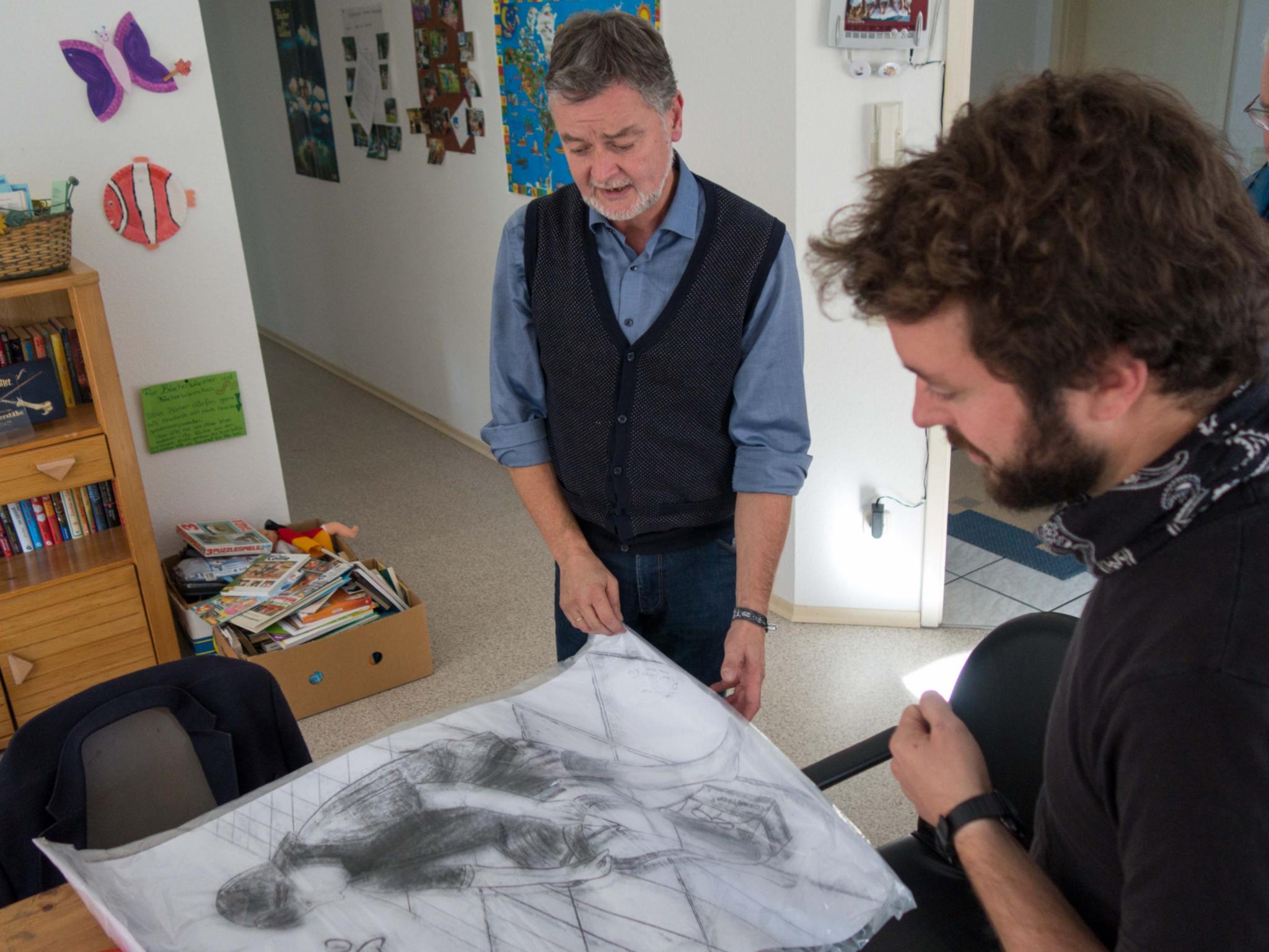 Eberhard Köhler (links) übergibt Jannis Ließfeld von der 'Casa Esperanza' ein Bild aus Bolivien. Es zeigt einen Jungen beim Schuheputzen.