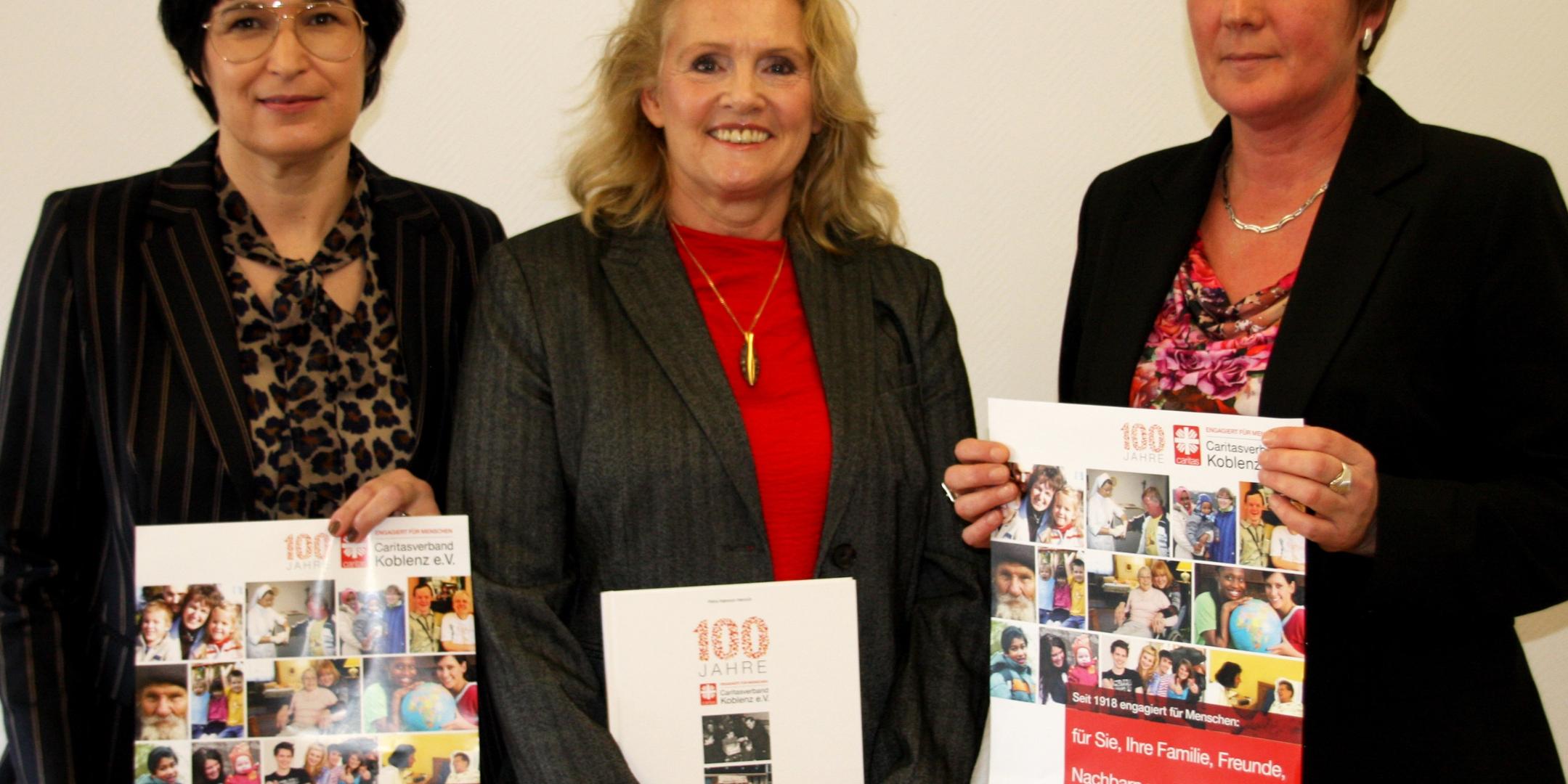 Vorsitzende des Caritasverbandes Koblenz Anette Moesta (links), Historikerin Petra Habrock-Heinrich (Mitte) und Caritasdirektorin Martina Best-Liesenfeld präsentieren das Jubiläumsprogramm und die Festschrift.
