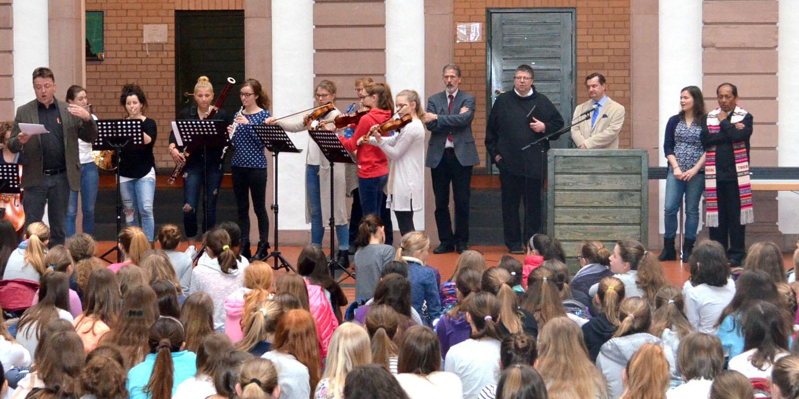 Im Hintergrund neben dem Orchester des AMG stehen von links nach rechts Ludwig Kuhn von der Diözesanstelle Weltkirche, Schulseelsorger Bruder Gregor, Direktor Dr. Mario Zeck und Erzbischof Ricardo Centellas.
