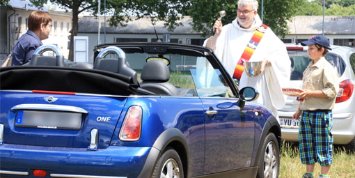 Oswald Jenni segnet eines der vielen Fahrzeuge. Ein Pfadfinder hält die Christophorus-Plakette schon bereit. (Foto: Ute Wagner / Dekanat Neunkirchen)