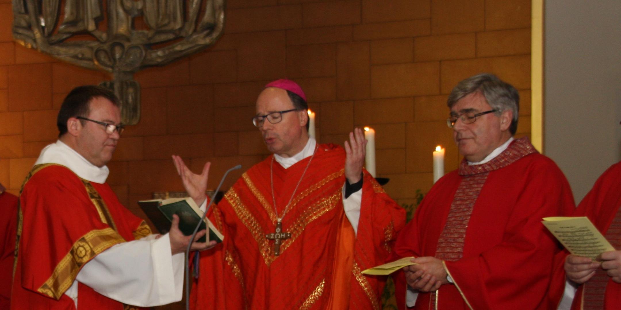 Bischof Ackermann und weitere Geistliche stehen vor der Gemeinde und predigen