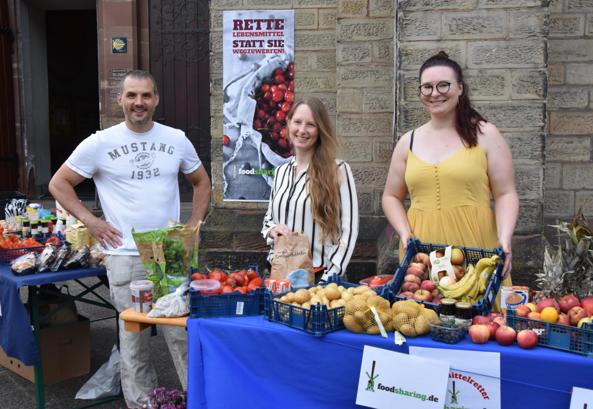 Sebastian Müller, Kirsten Brackertz und Annabelle Jung von Foodsharing Saarbrücken haben vor der Kirche zur Eröffnung ein Buffett aus geretteten Lebensmitteln aufgebaut. Bildquelle: Ute Kirch/Bischöfliche Pressestelle