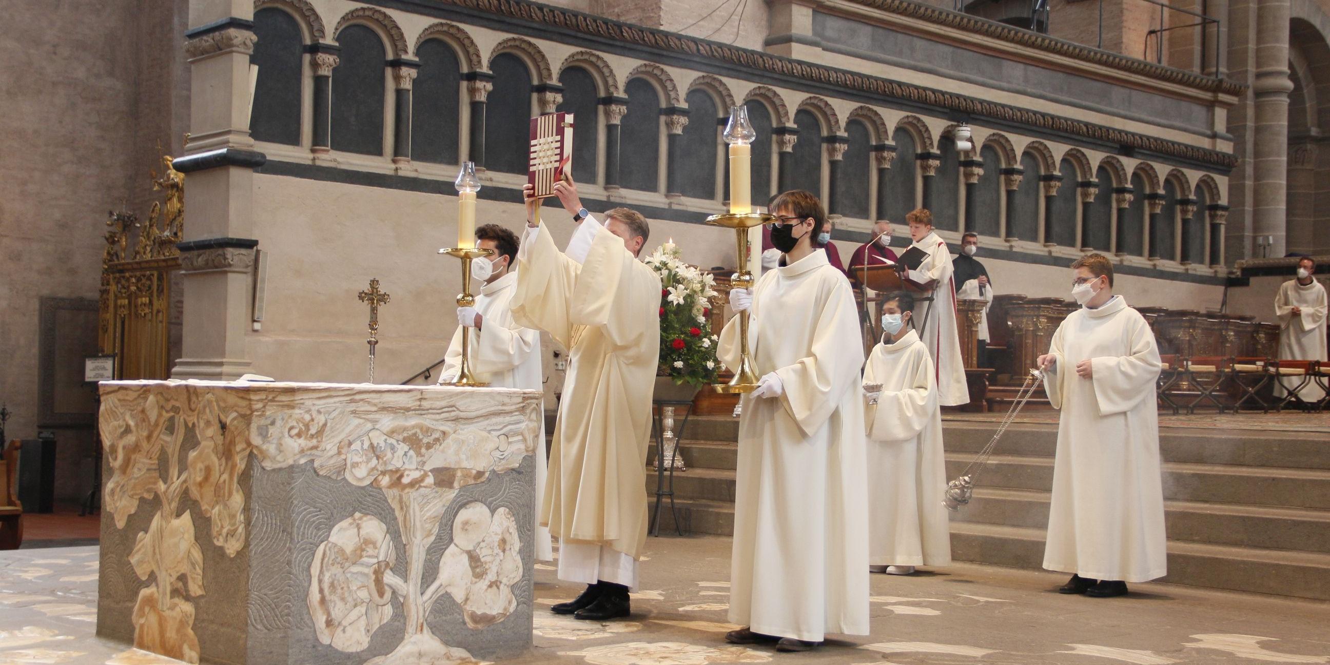 Seit vielen Jahrhunderten wird im Trierer Dom Gottesdienst gefeiert. Diakon Ulrich Weinand zeigt der Gottesdienstgemeinde das Evangeliar, bevor er das Evangelium verkündet.