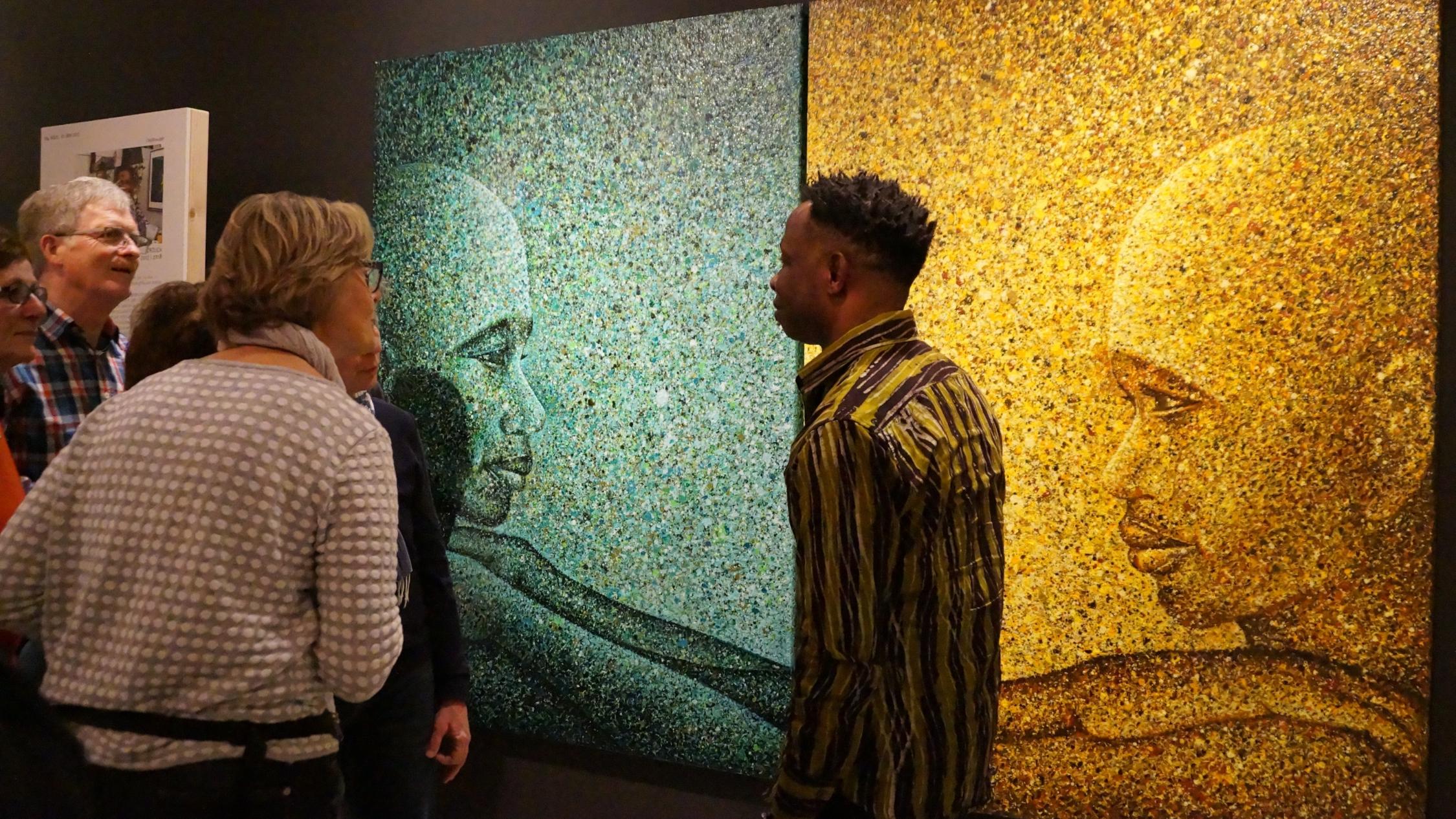 Interessiert folgen Ausstellungsgäste den Erklärungen des nigerianischen Künstlers Chidi Kwubiri über seine „Dripping-Technik“, eine spezielle Farb-Tropf-Technik.