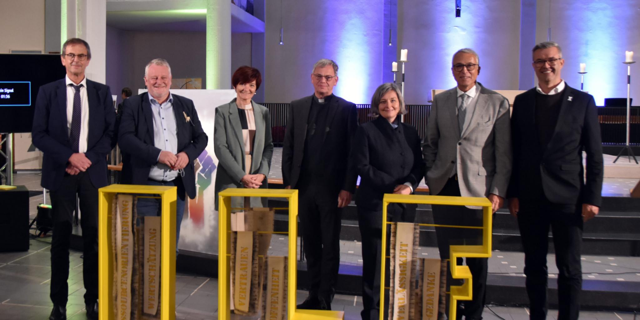 GWB-Geschäftsführer Joachim Jung-Sion, SPD-Landtagsfraktions-Vorsitzender Ulrich Commerçon, Ordinariatsdirektorin Katja Göbel, Generalvikar Dr. Ulrich Graf von Plettenberg, Prof. Dr. Viera Pirker, Horst Heller vom religionspädagogischen Zentrum (Evangelische Kirche der Pfalz) und ILF-Leiter Thomas Mann beim Festakt in der Jugendkirche eli.ja in Saarbrücken. Foto: Ute Kirch/Bistum Trier