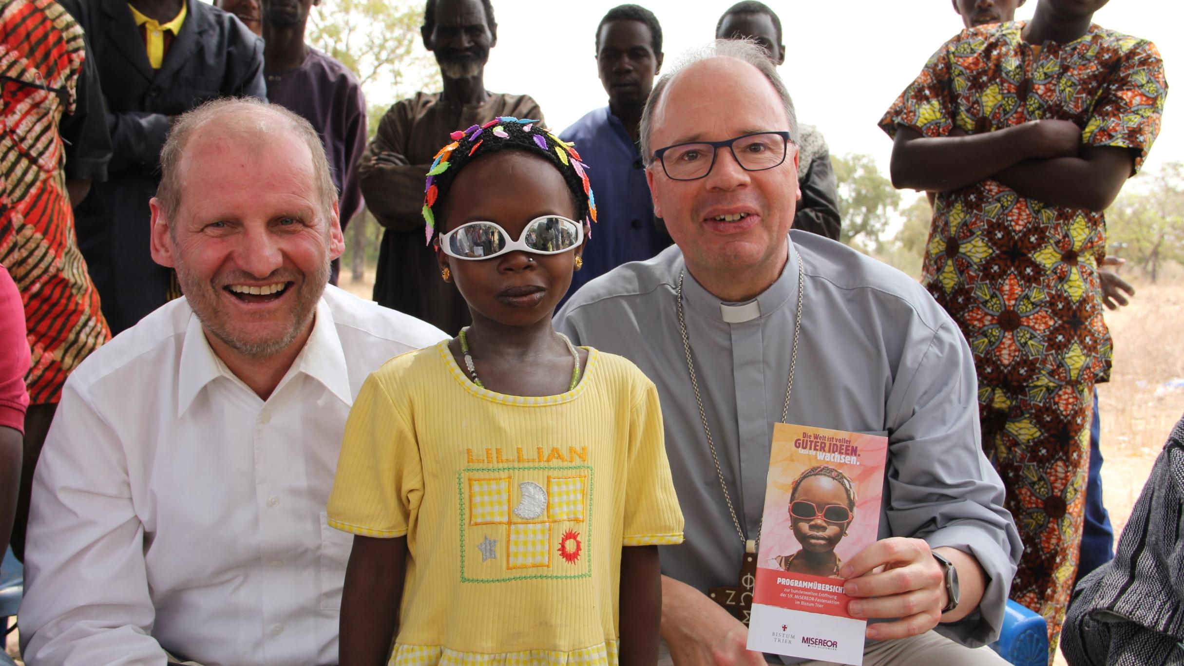 Die Welt aus einer anderen Perspektive sein, zum Beispiel mit umgedrehter Brille: Wie das geht, zeigt Balkissa Aljenatou Bischof Ackermann (re.) und Msgr. Spiegel. Sie ist auch auf dem diesjährigen Misereor-Plakat zu sehen.