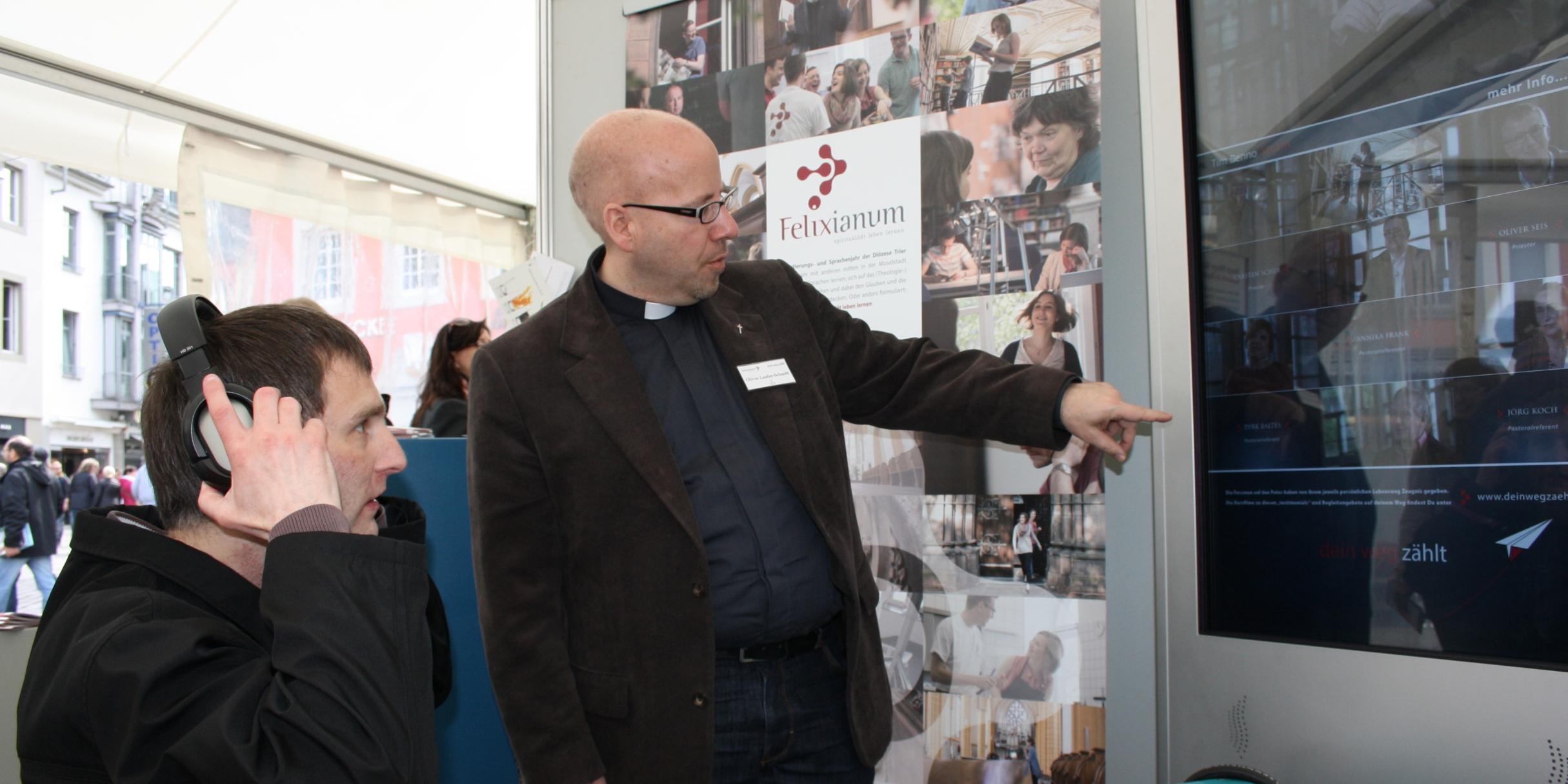 Oliver Laufer-Schmitt (rechts) hilft einem Besucher, an der Videostele den passenden Film zum Berufswunsch „Gemeindereferent“ zu finden.