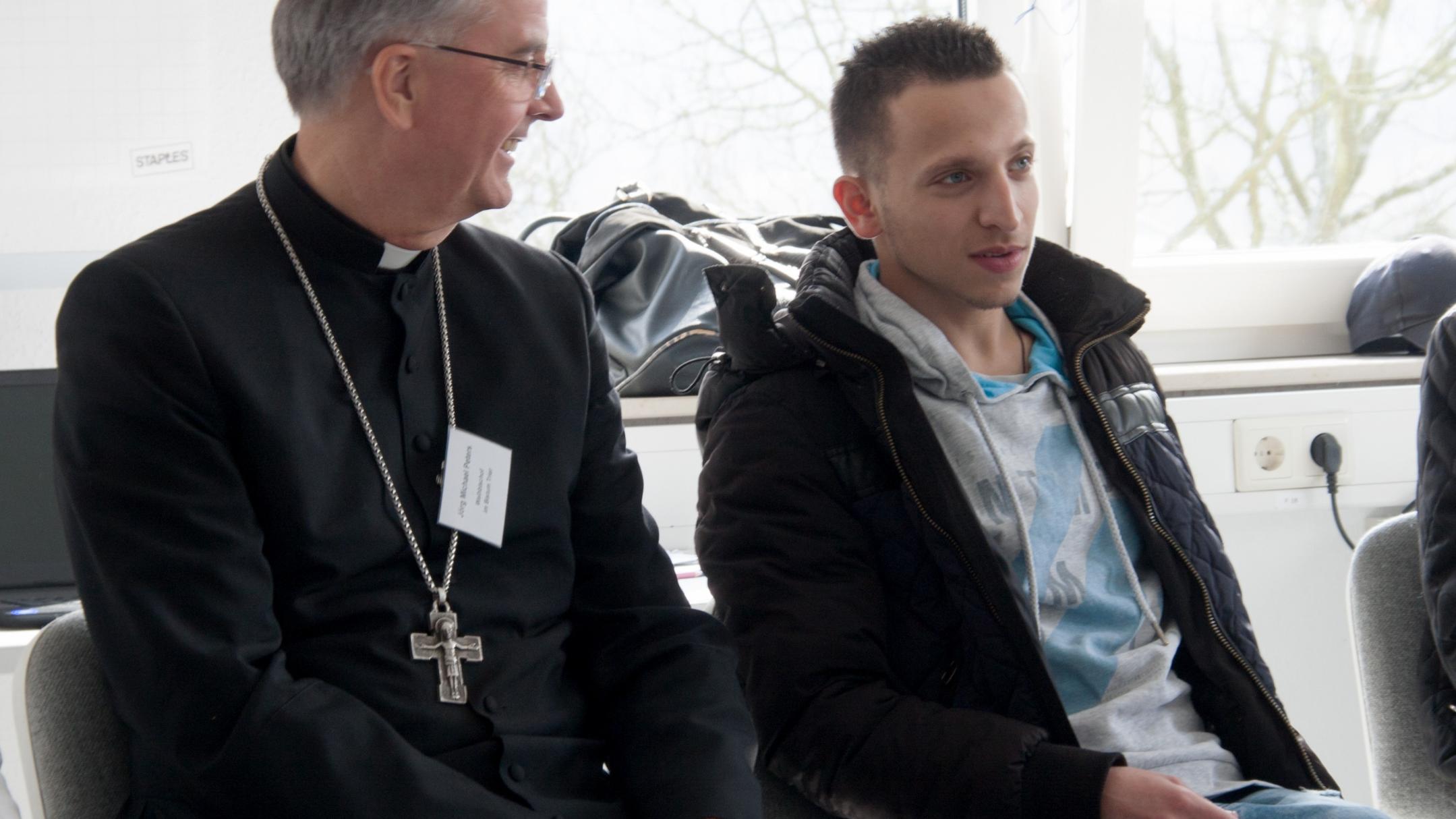 Weihbischof Peters im Gespräch mit einem jungen Mann, der einen Jugendintegrationskurs besucht.